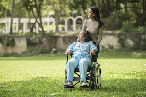 A woman in a wheelchair standing next to a man in a park