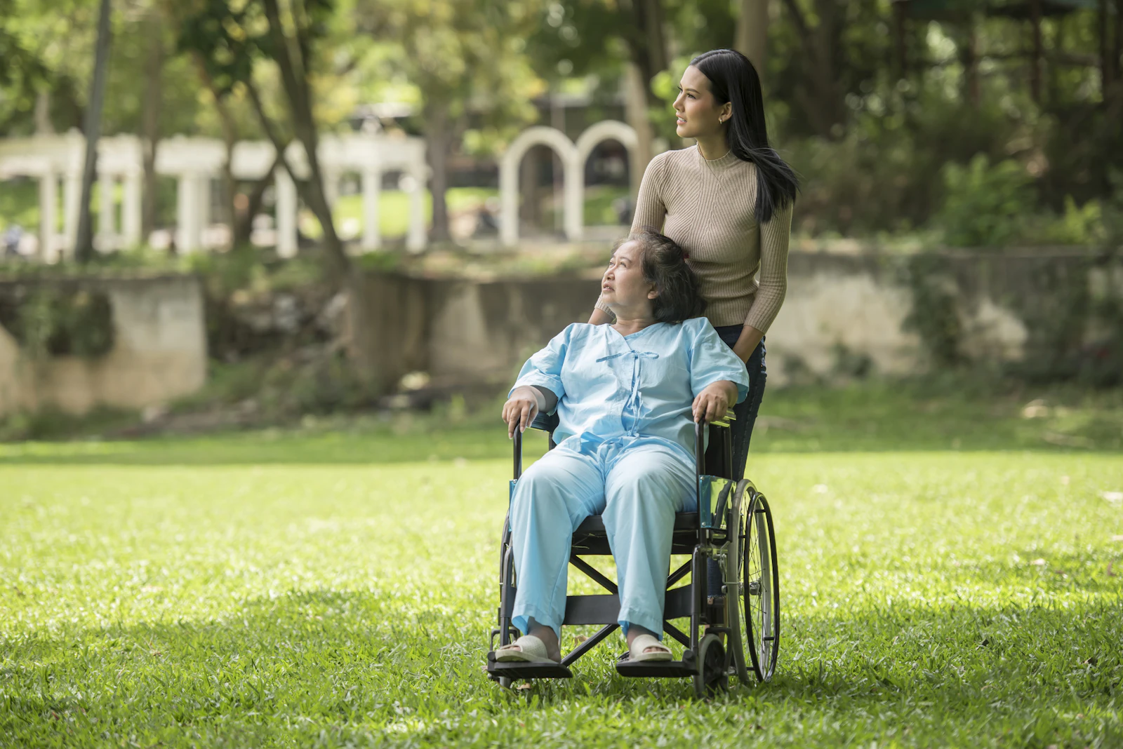 A woman in a wheelchair beside a man in a park