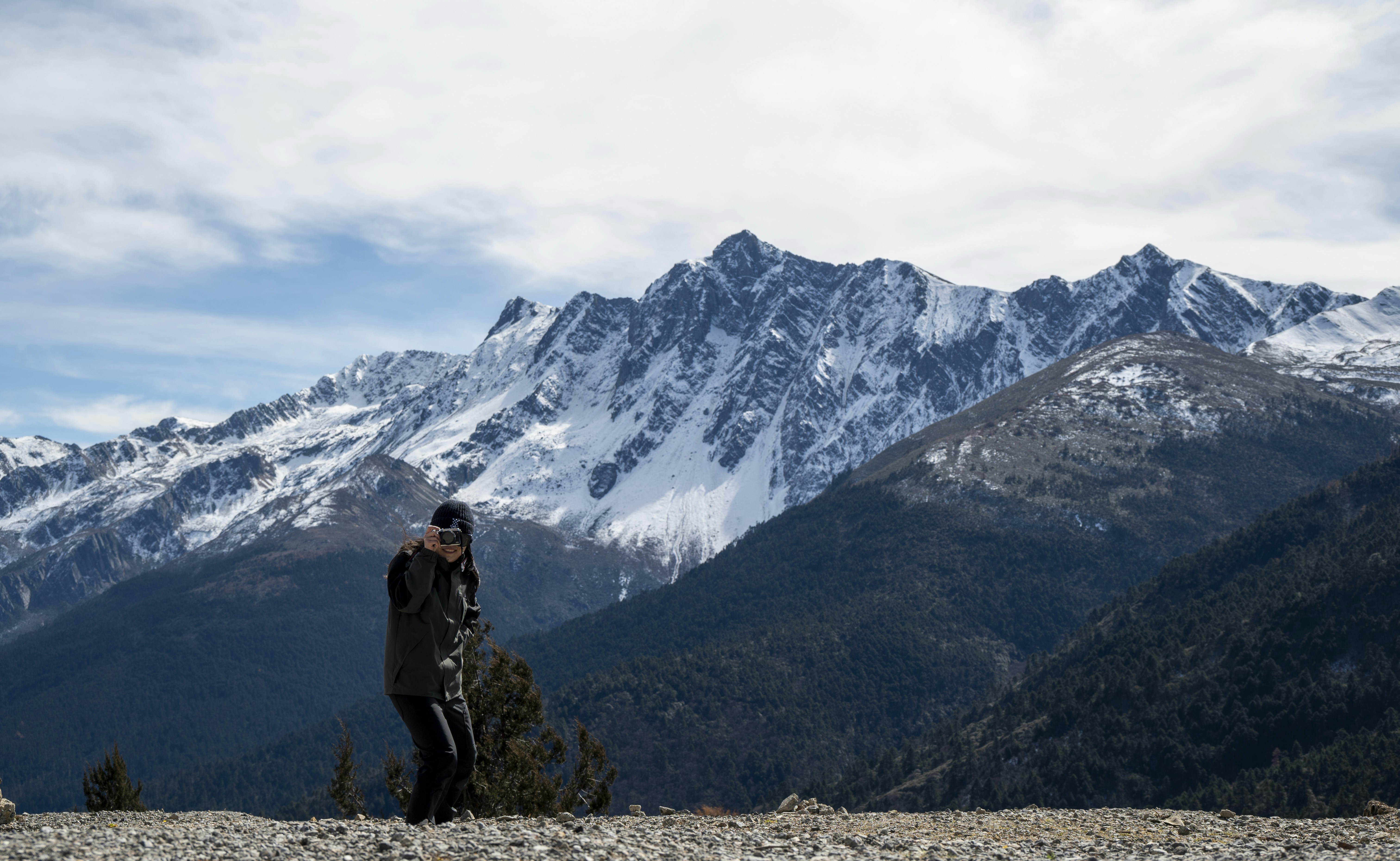 Une personne debout sur un sommet de montagne, regardant un vaste paysage, symbolisant le leadership et la vision.