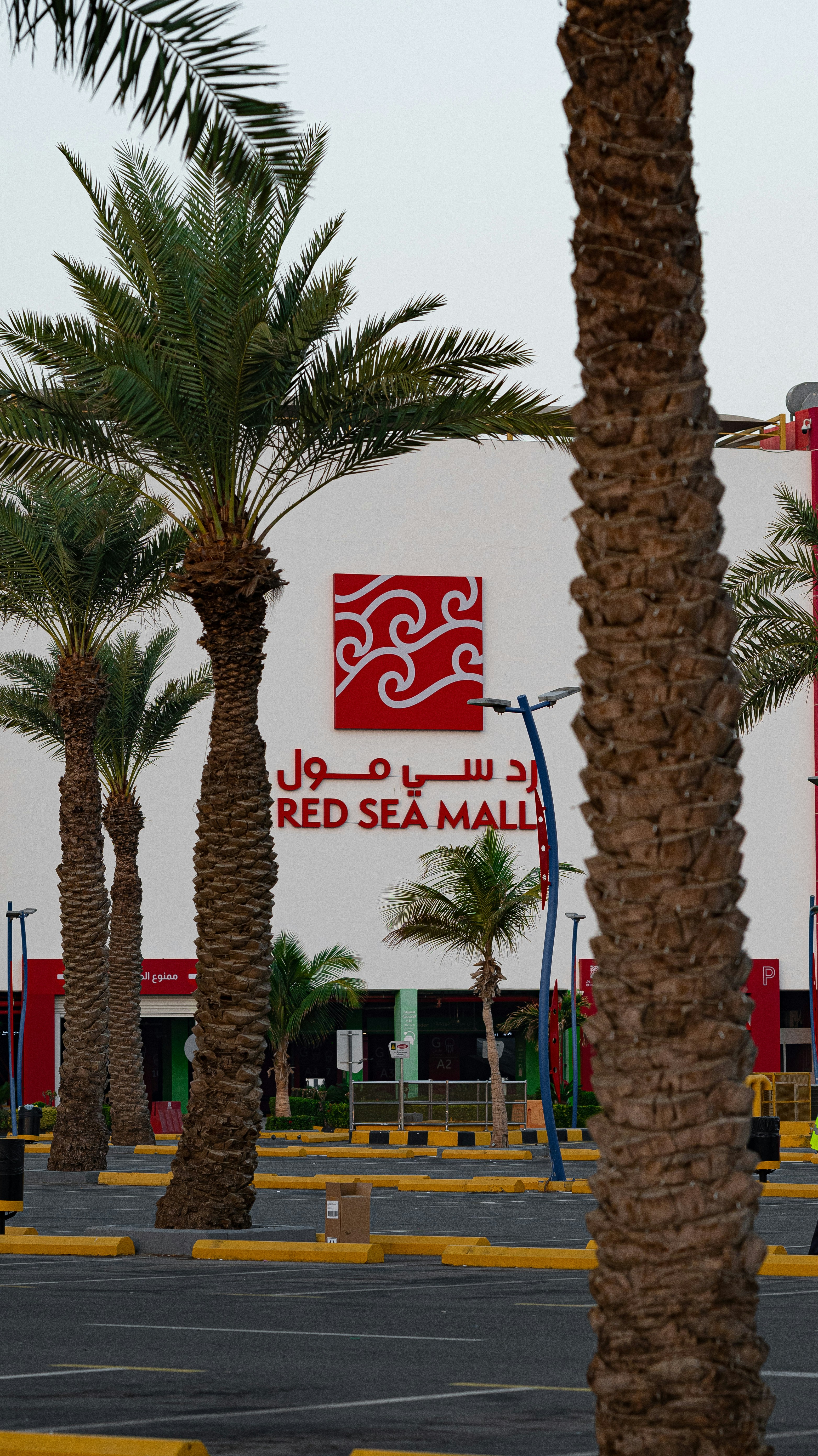 A red sea mall with palm trees in front of it