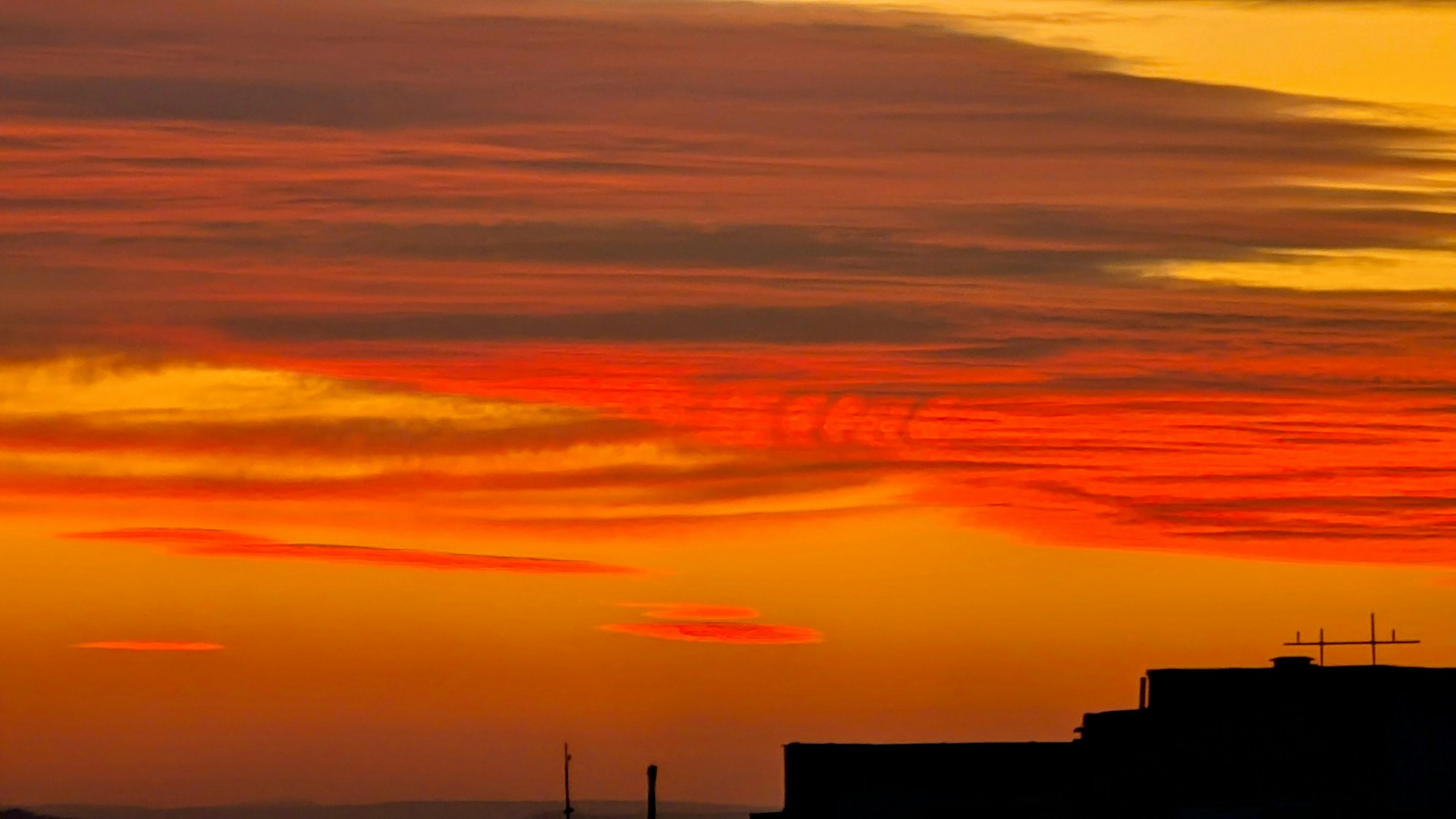 A red and yellow sky with a building in the foreground