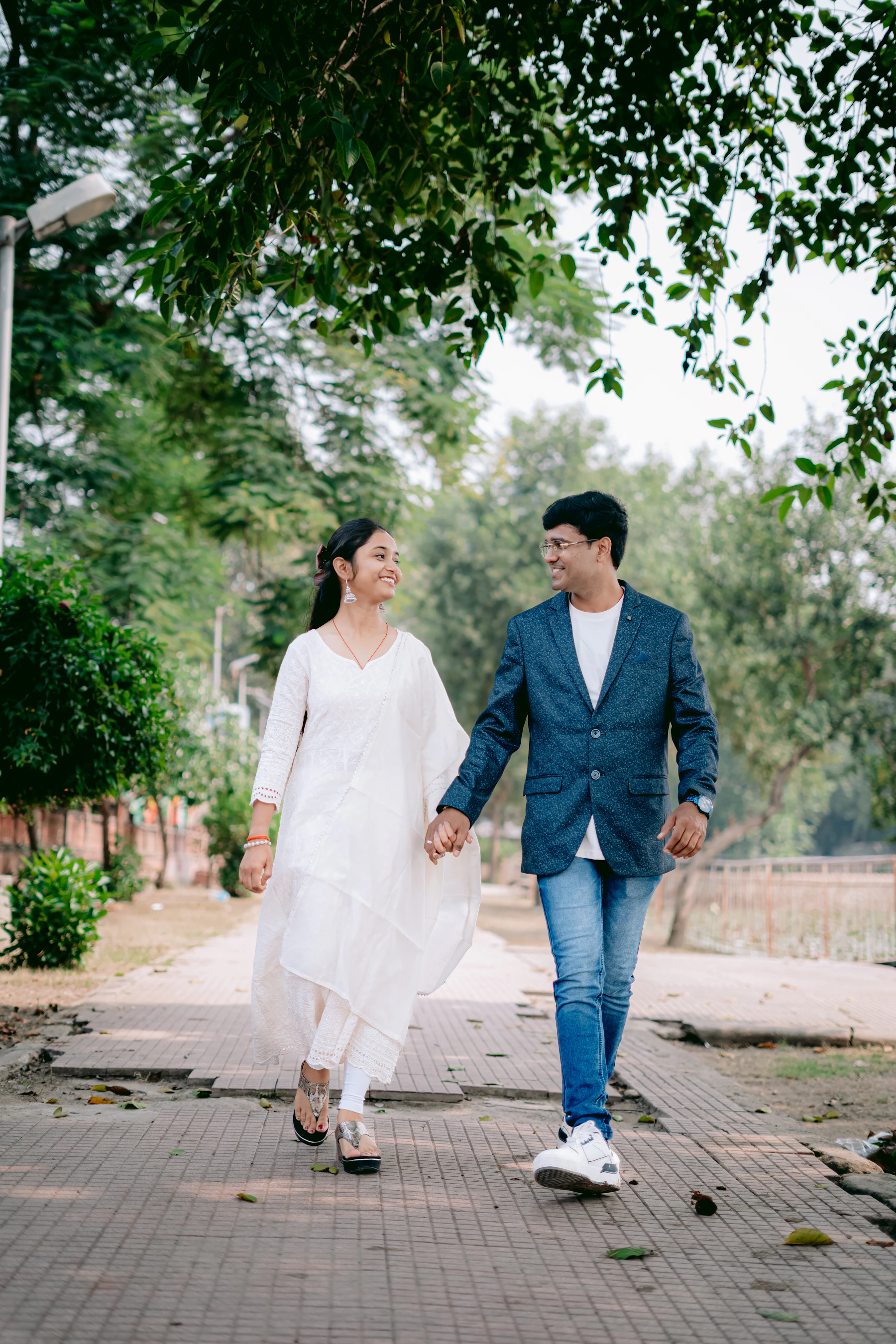A couple walking hand in hand along a leafy path