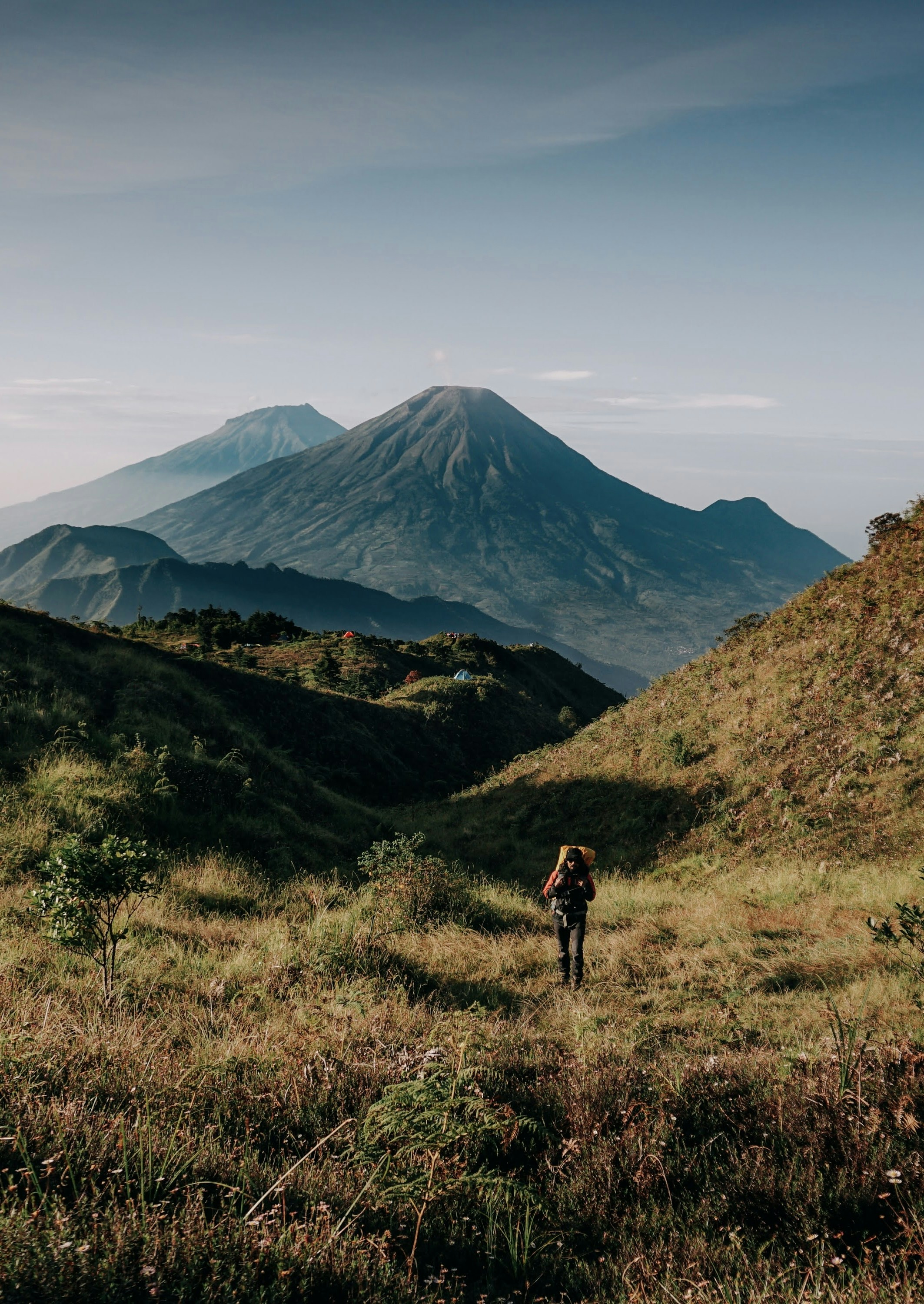 A person hiking up a hill with a mountain in the background