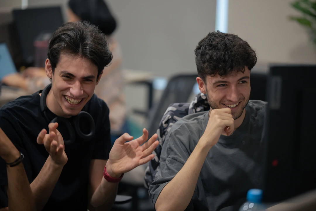 Two engineers laughing together while working at a computer