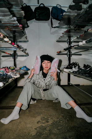 A person sitting on the ground holding a pair of shoes