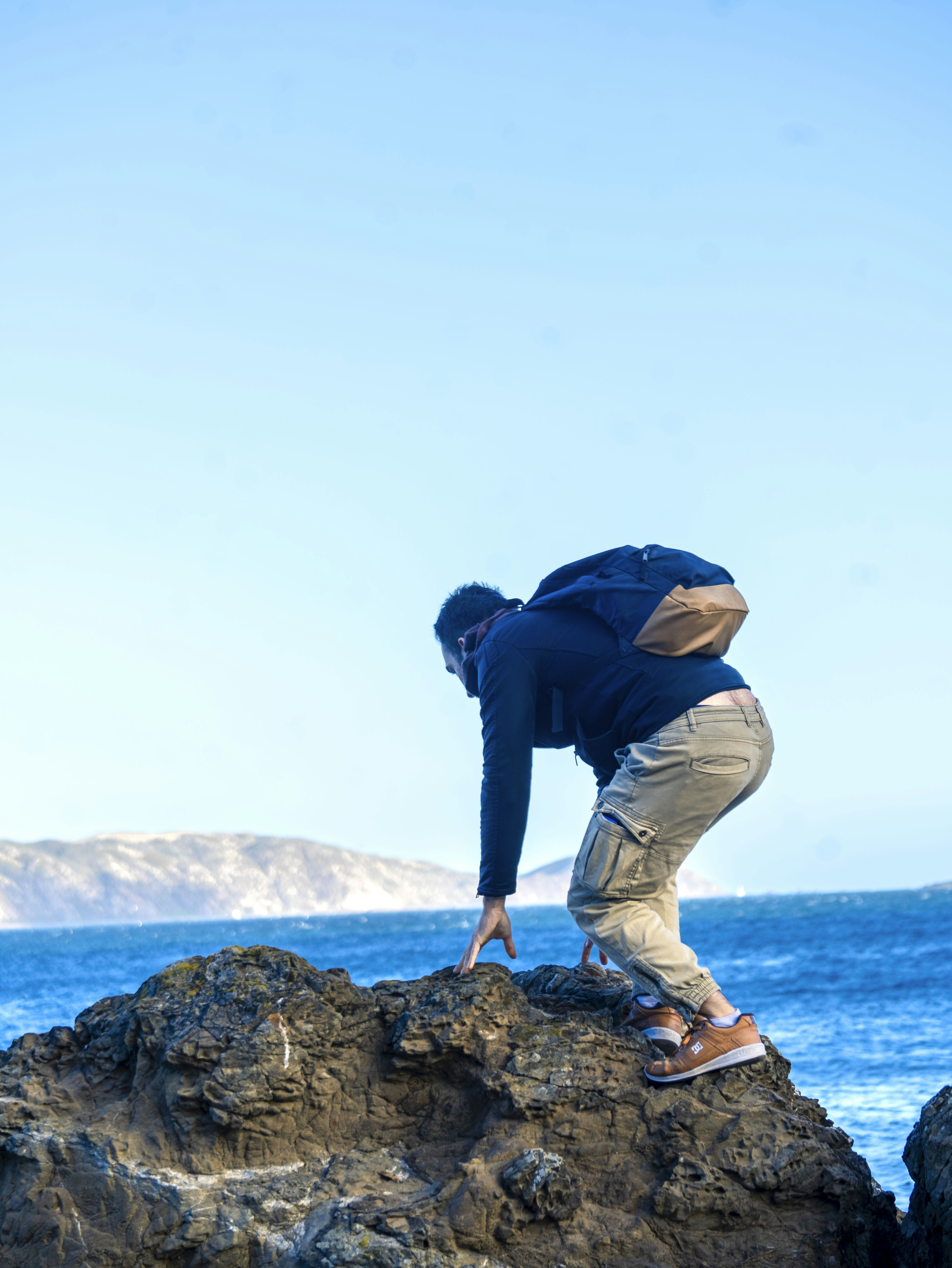 Uma pessoa em pé no topo de uma rocha perto do oceano