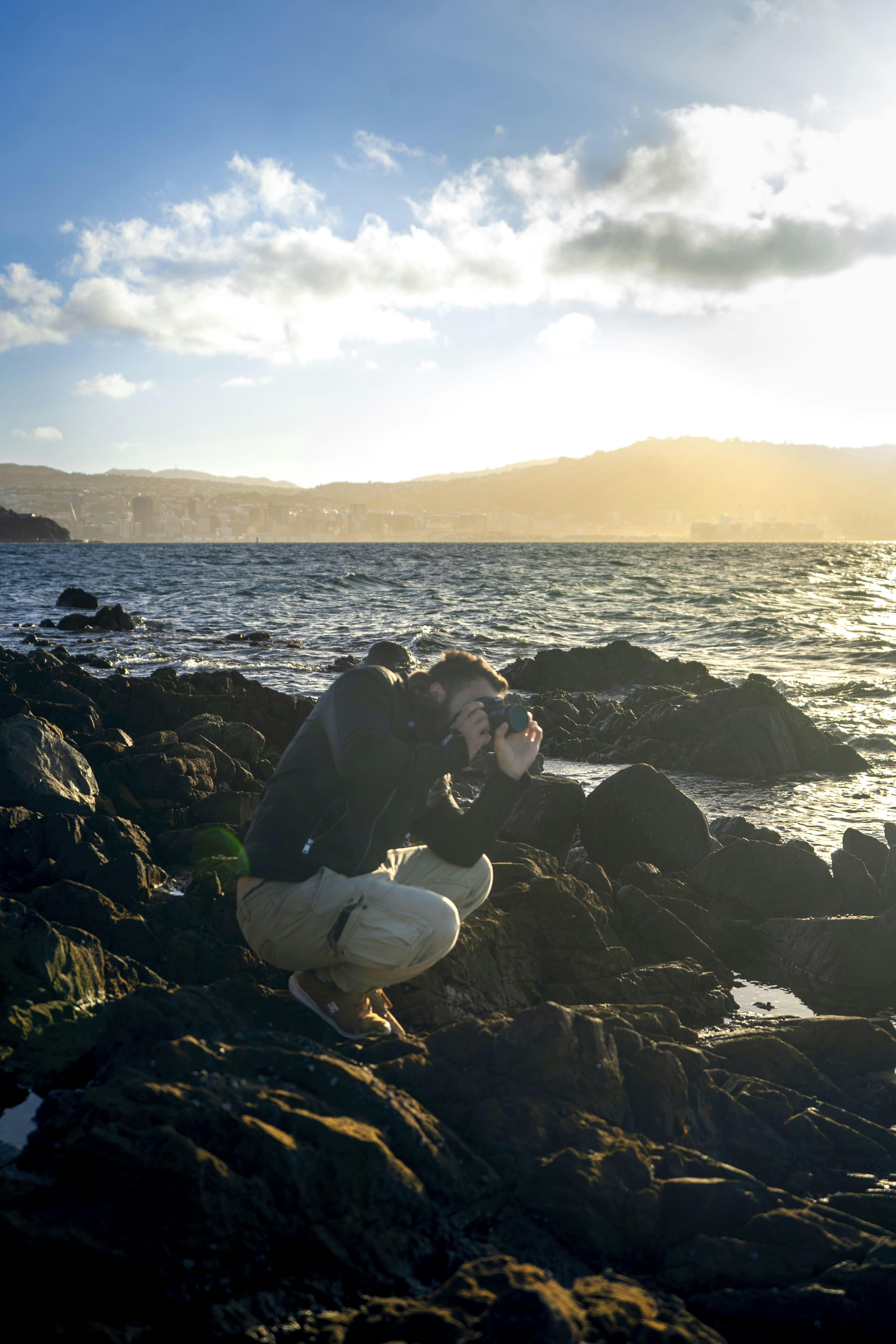 A man kneeling on a rock next to the ocean photo – Free Nature Image on ...