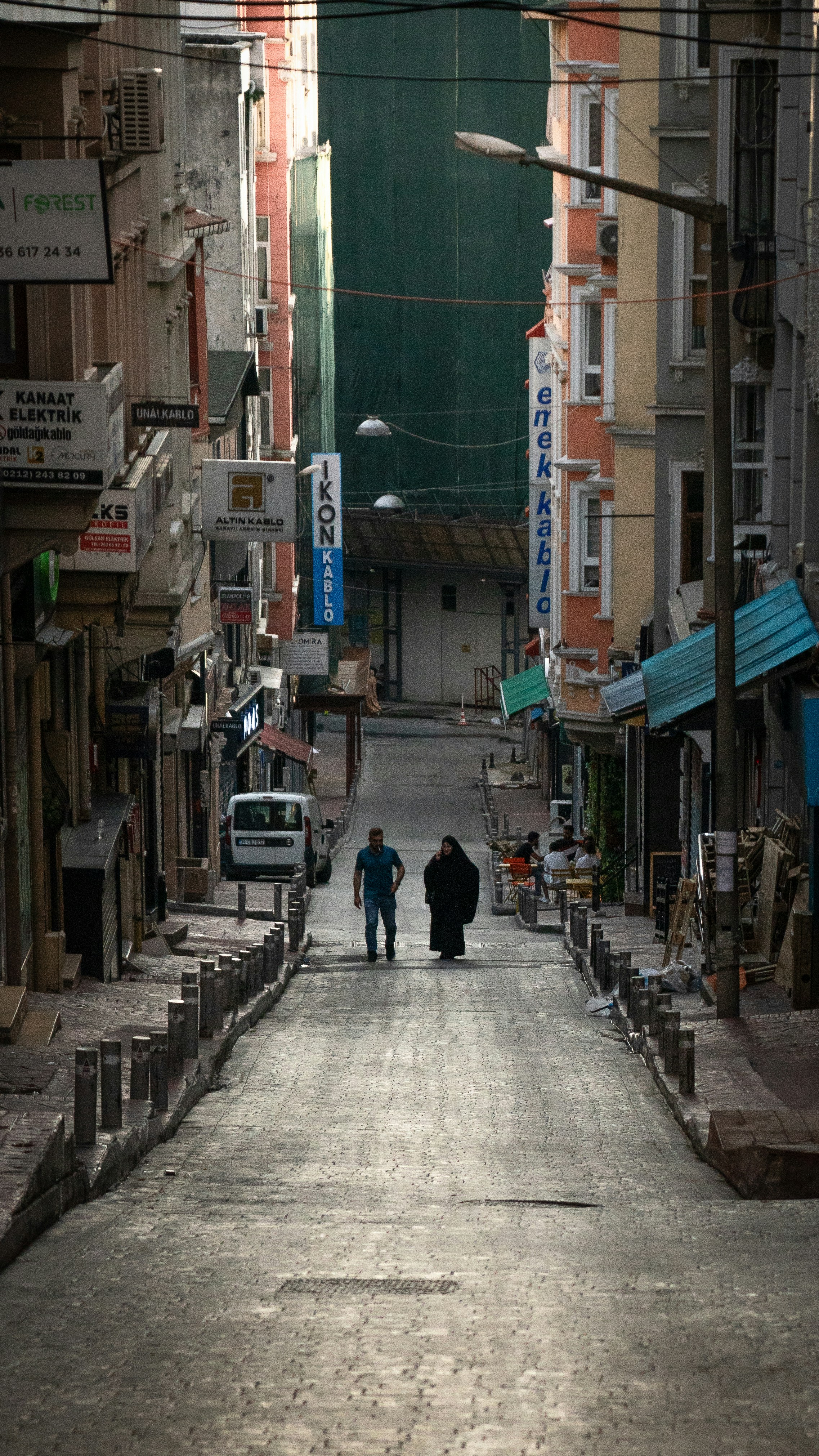 A couple of people walking down a street next to tall buildings