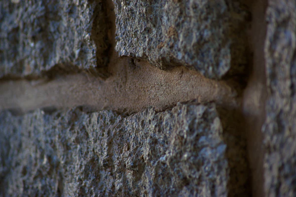 A close detail of a stacked stone wall with a mortar joint.