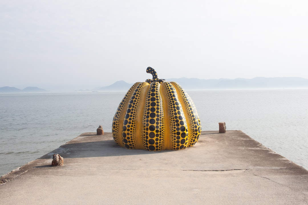 A large pumpkin sitting on top of a pier next to the ocean