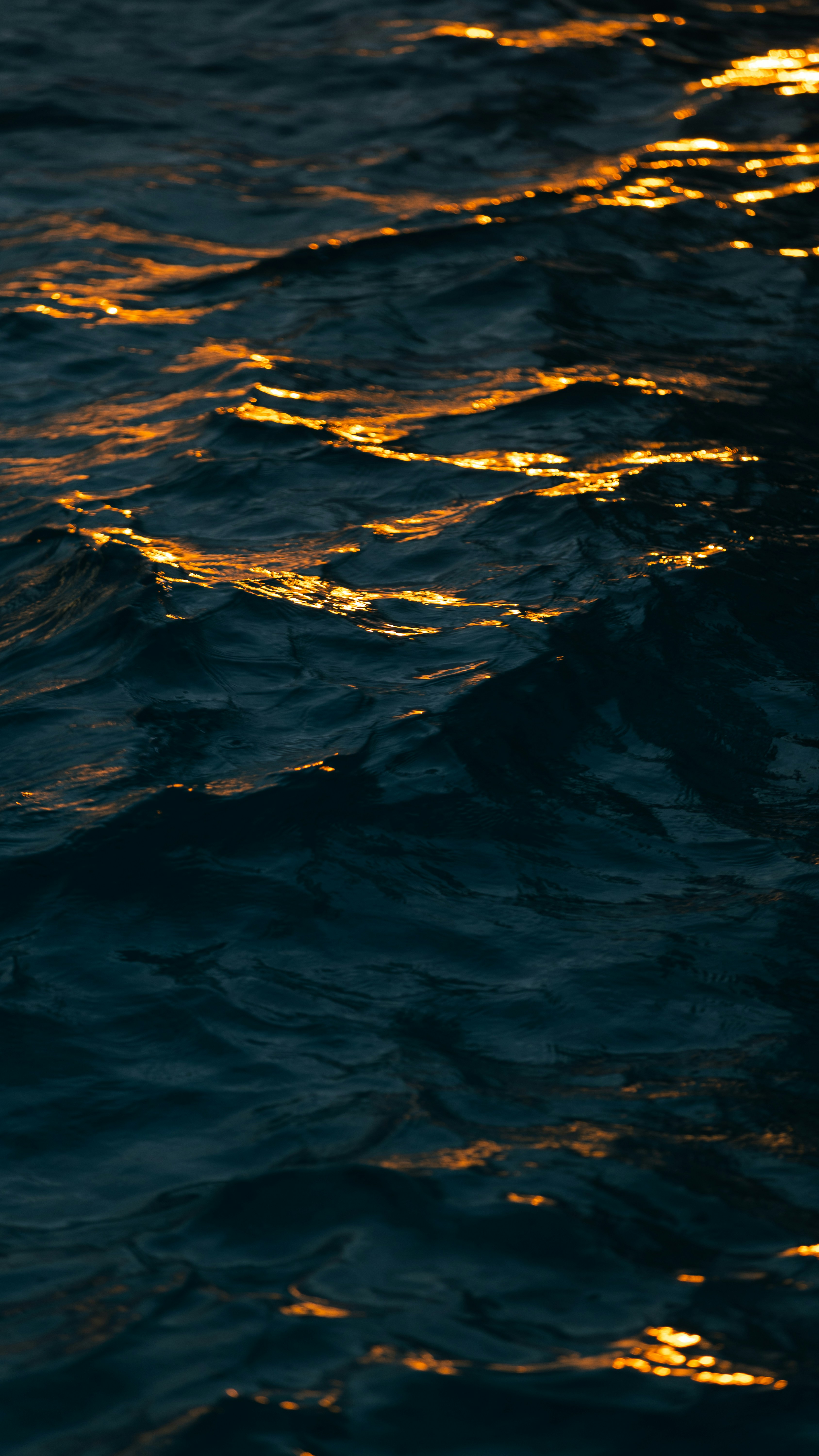 Golden light reflecting on the dark rippling surface of deep water