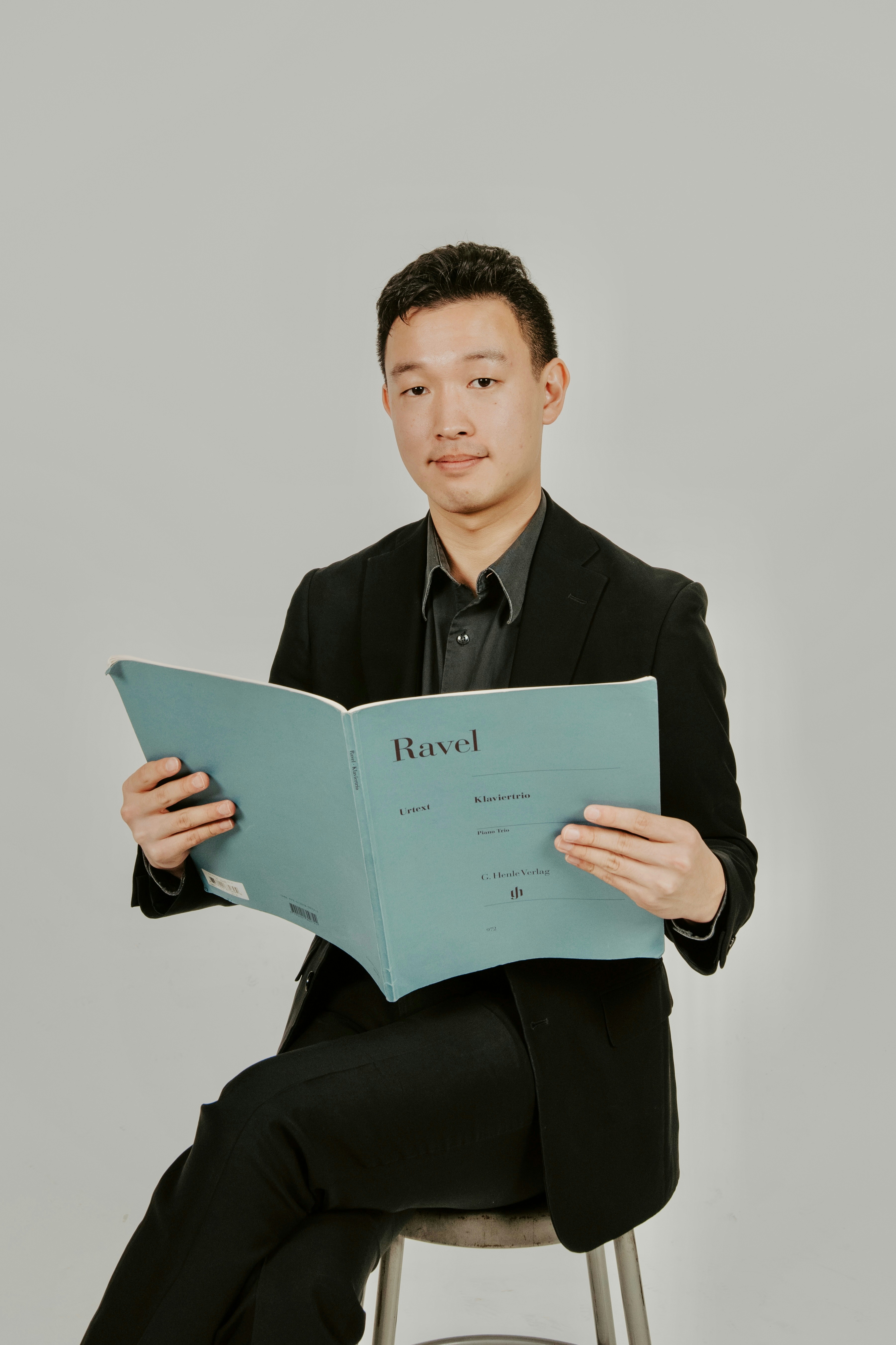 A man sitting on a stool reading a book