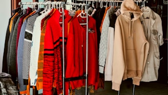 A rack of clothes in a closet with clothes hanging on it