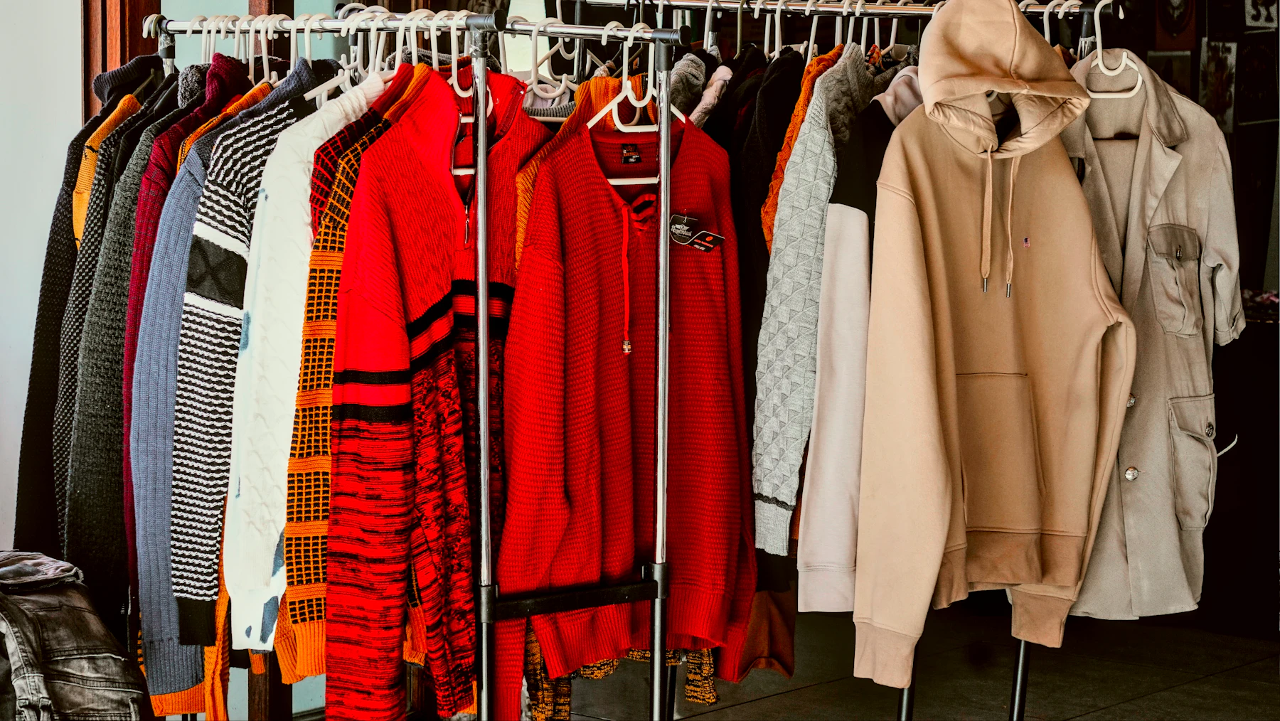 A rack of clothes in a closet with clothes hanging on it
