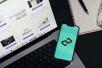 A cell phone sitting on top of a desk next to a laptop