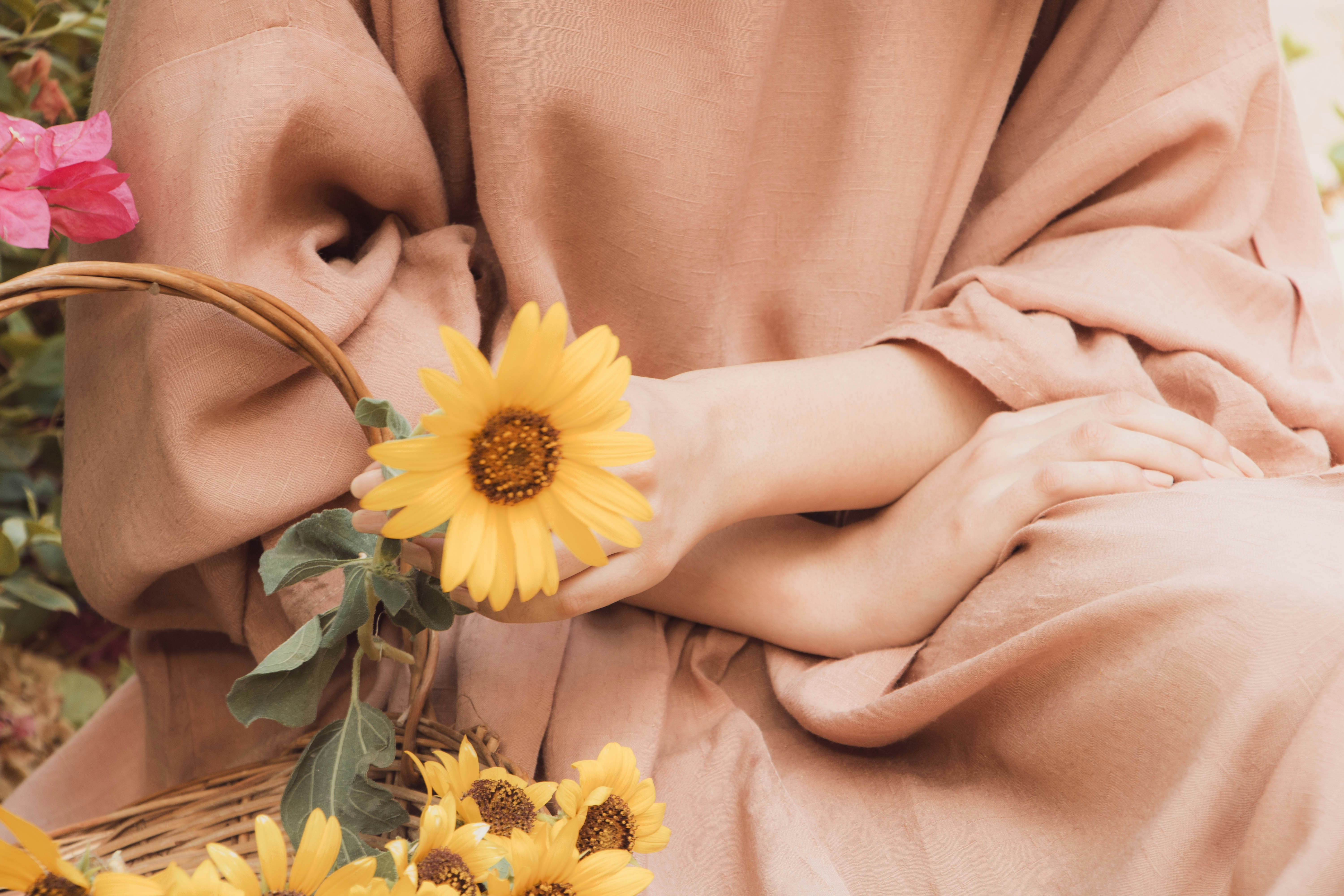 Una mujer sentada en un banco con una cesta de girasoles