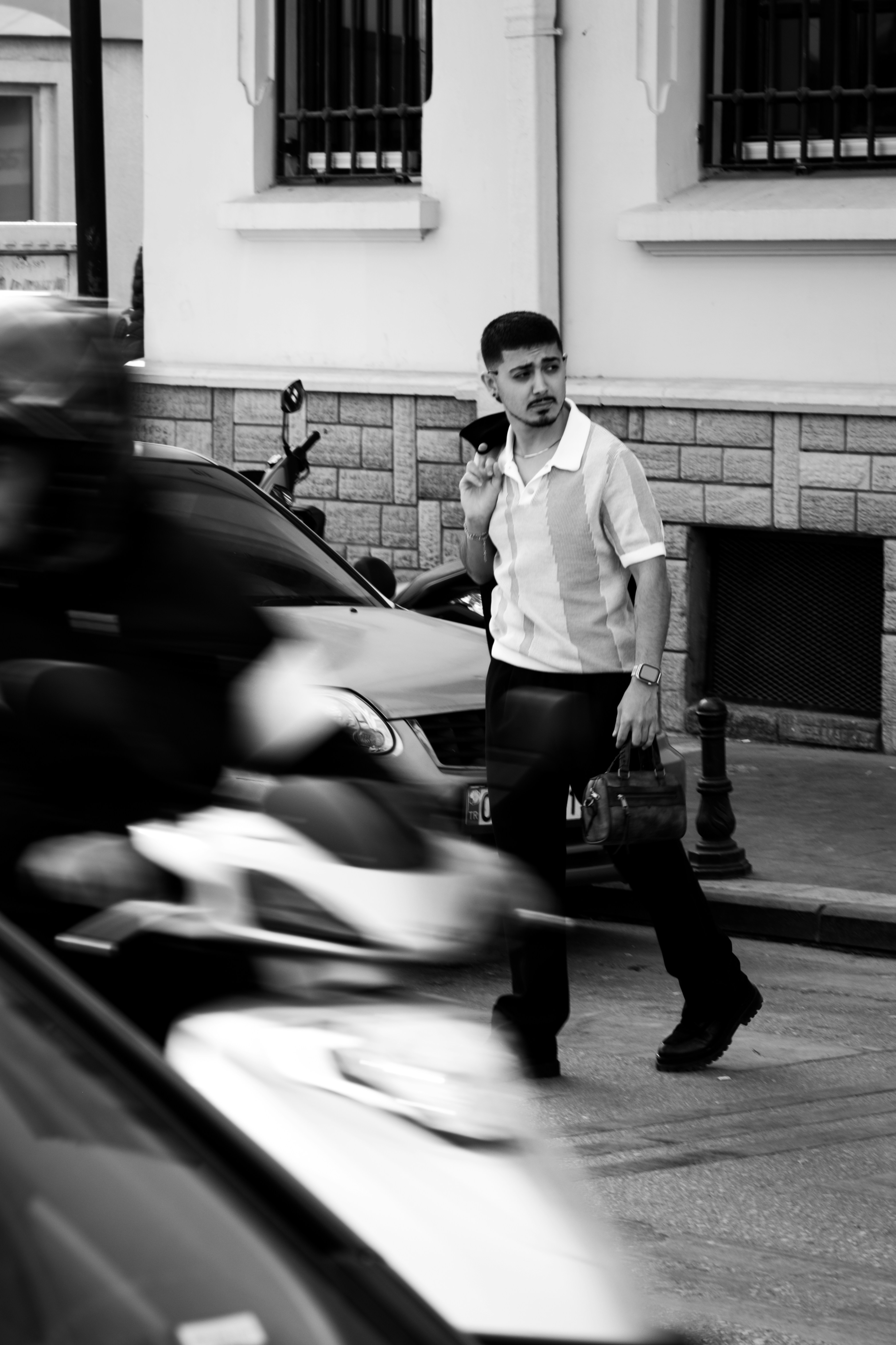 駐車中の車の横を歩いている男性