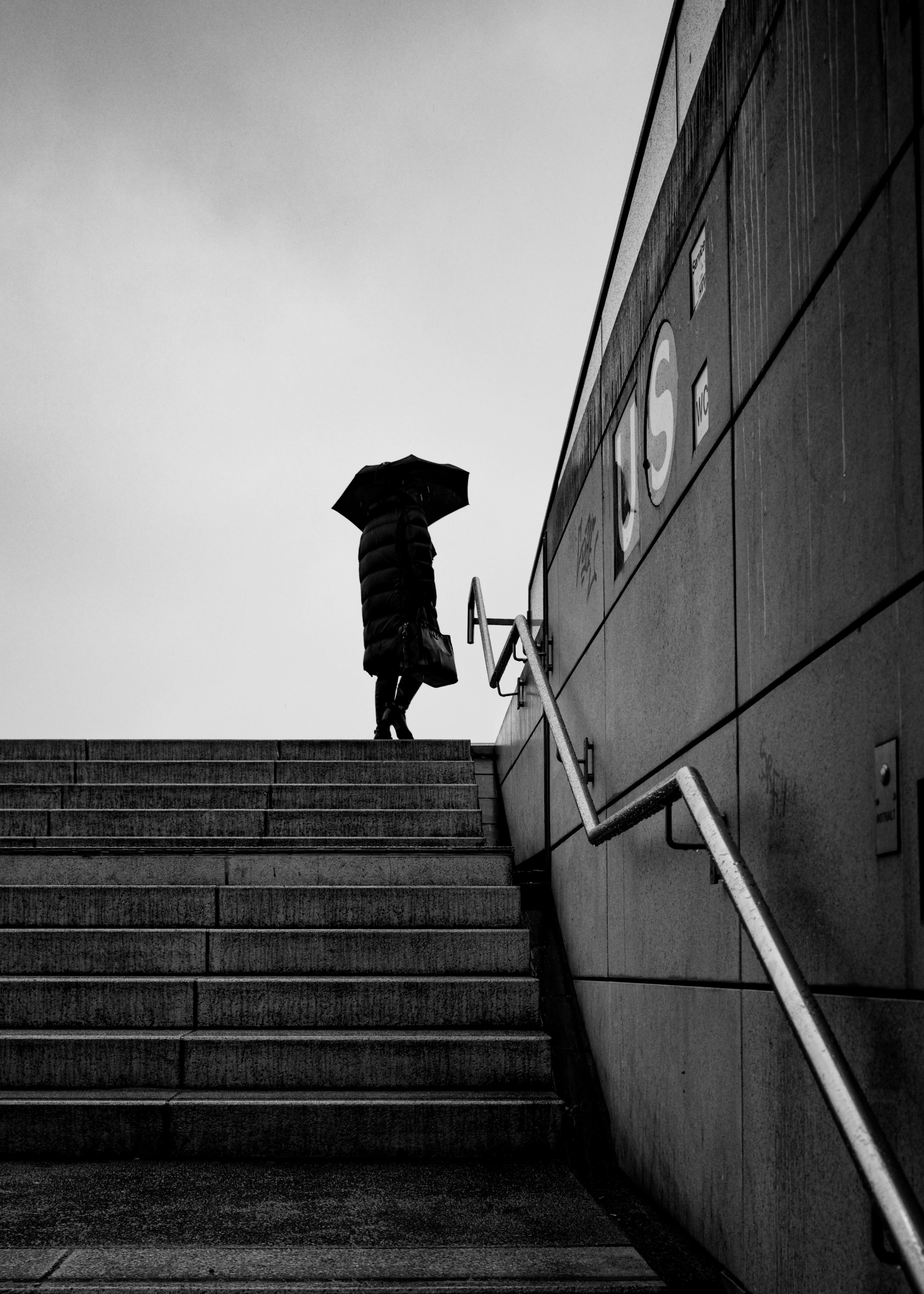 Uma pessoa com um guarda-chuva subindo um lance de escadas