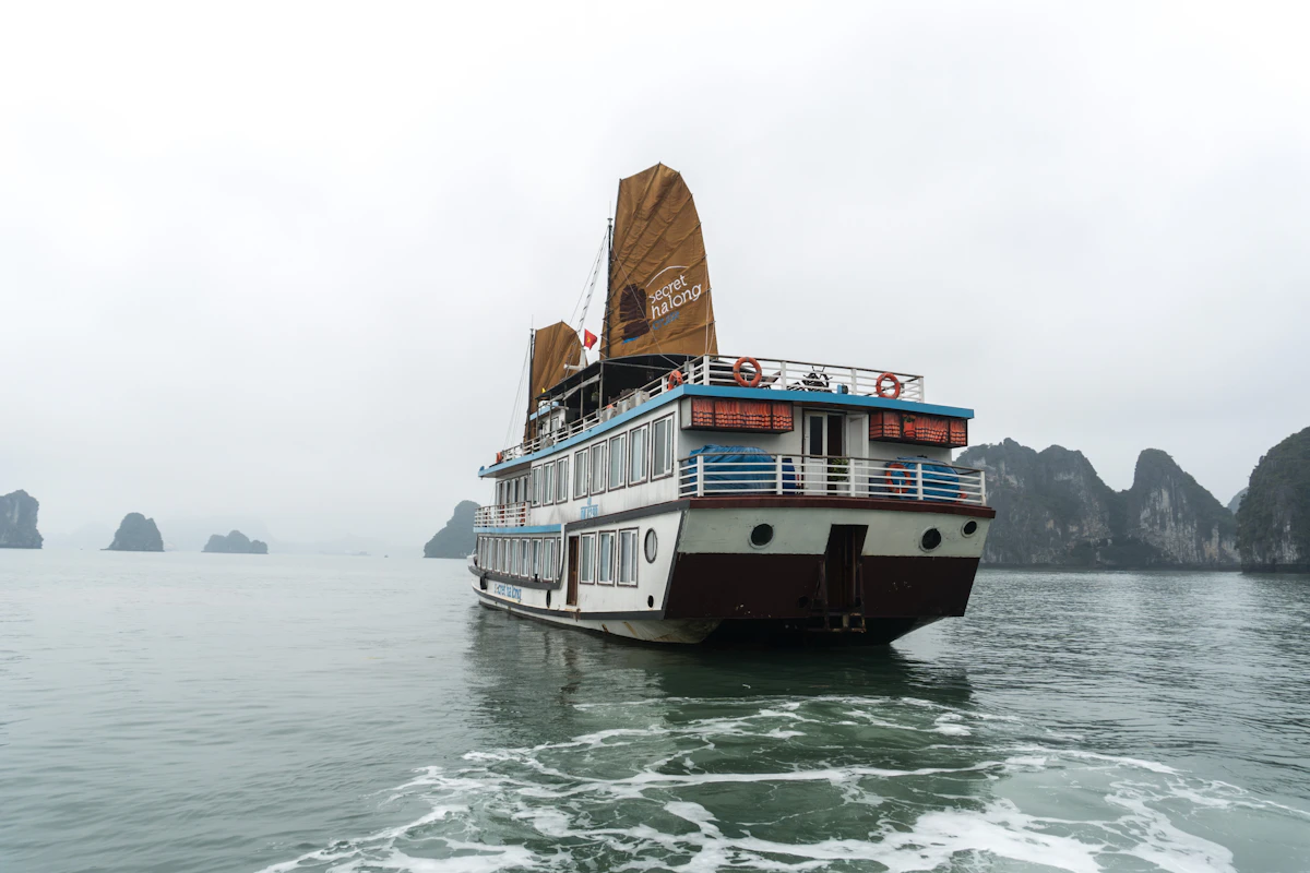 Private junk anchored in an isolated Halong Bay inlet surrounded by karst towers at sunrise