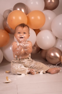 A baby sitting in front of a bunch of balloons