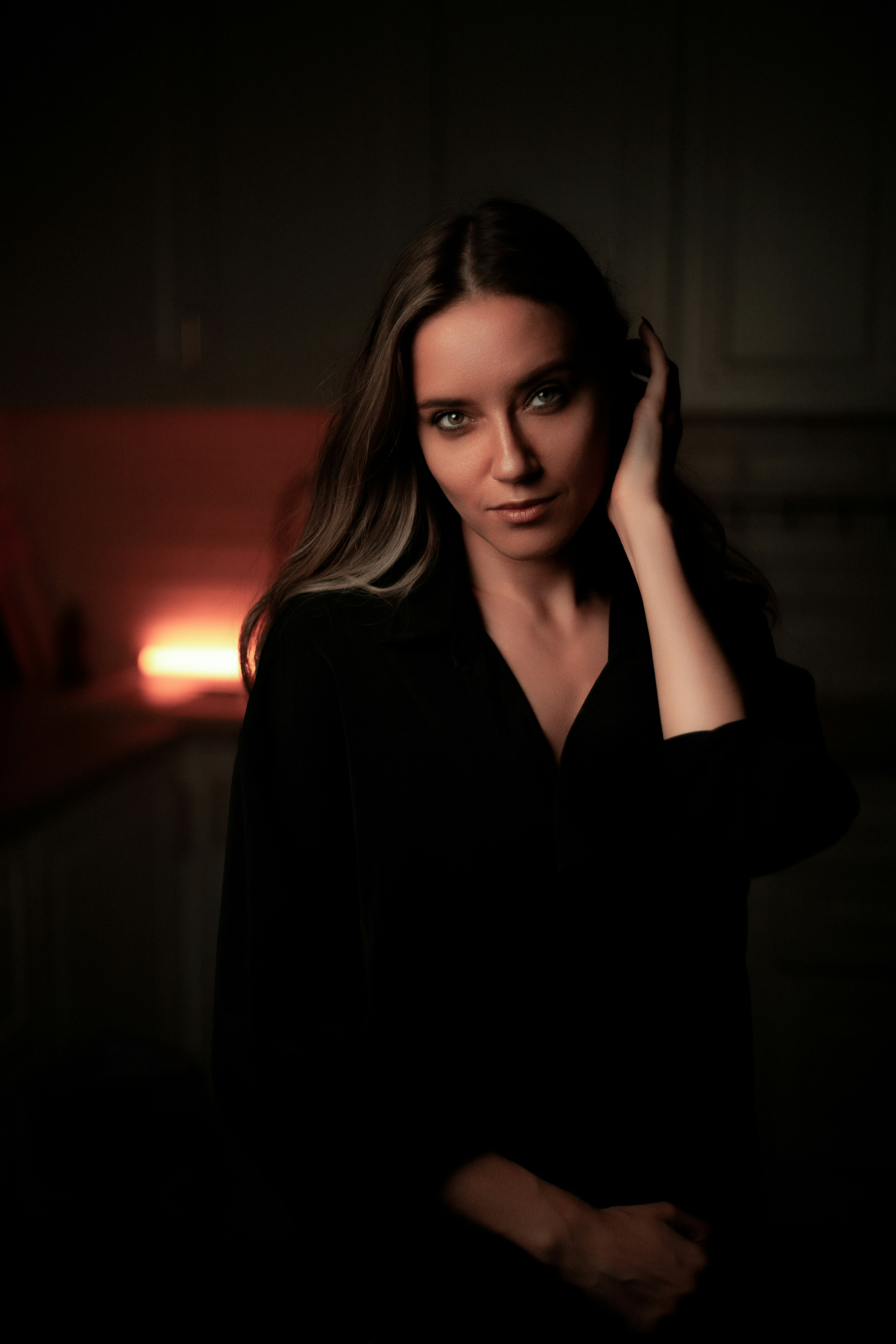 A woman standing in a dark room with her hand on her head