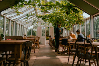 A group of people sitting at tables inside of a greenhouse
