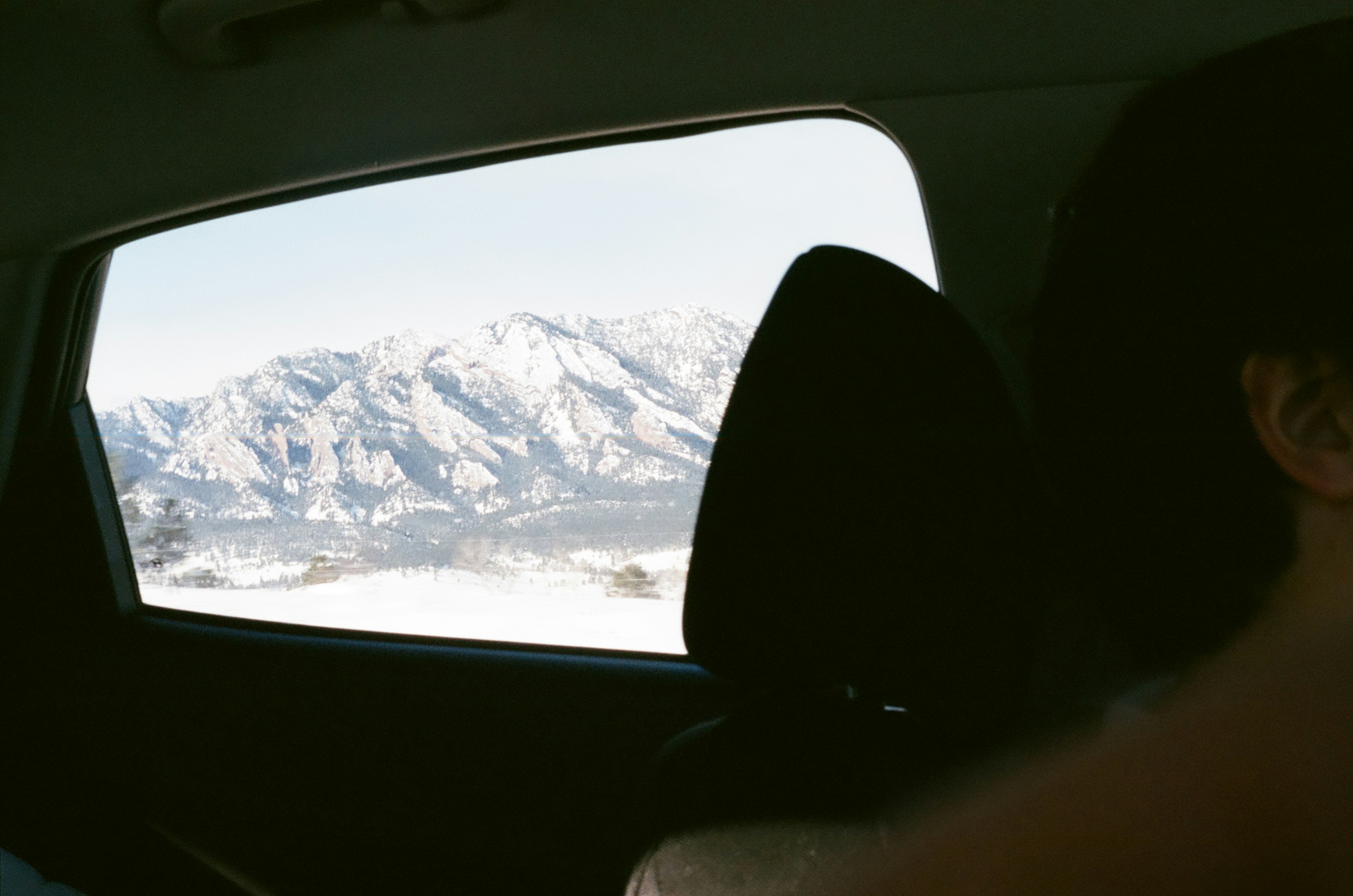 A view of a snowy mountain from inside a car