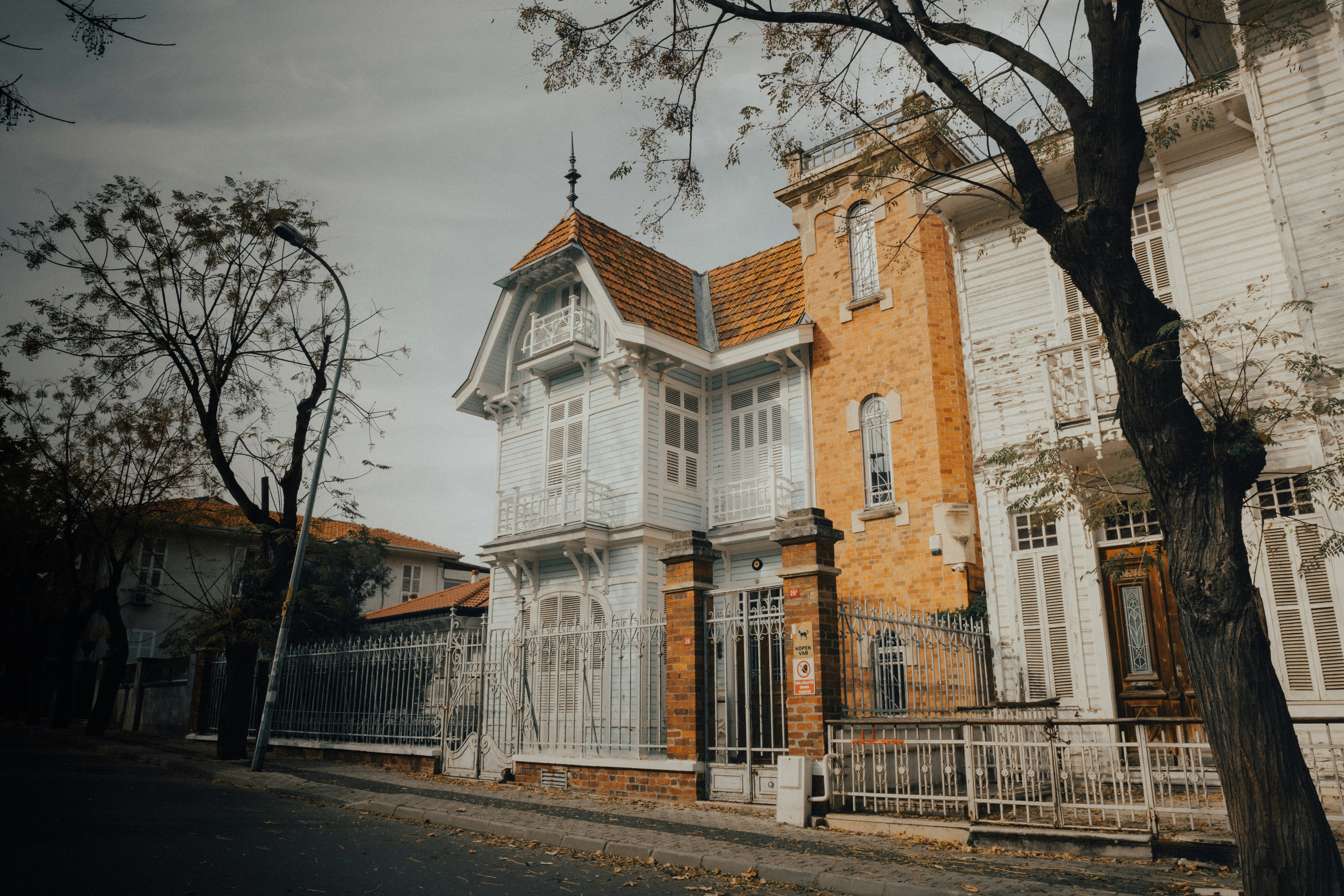 A house with a fence and a tree in front of it