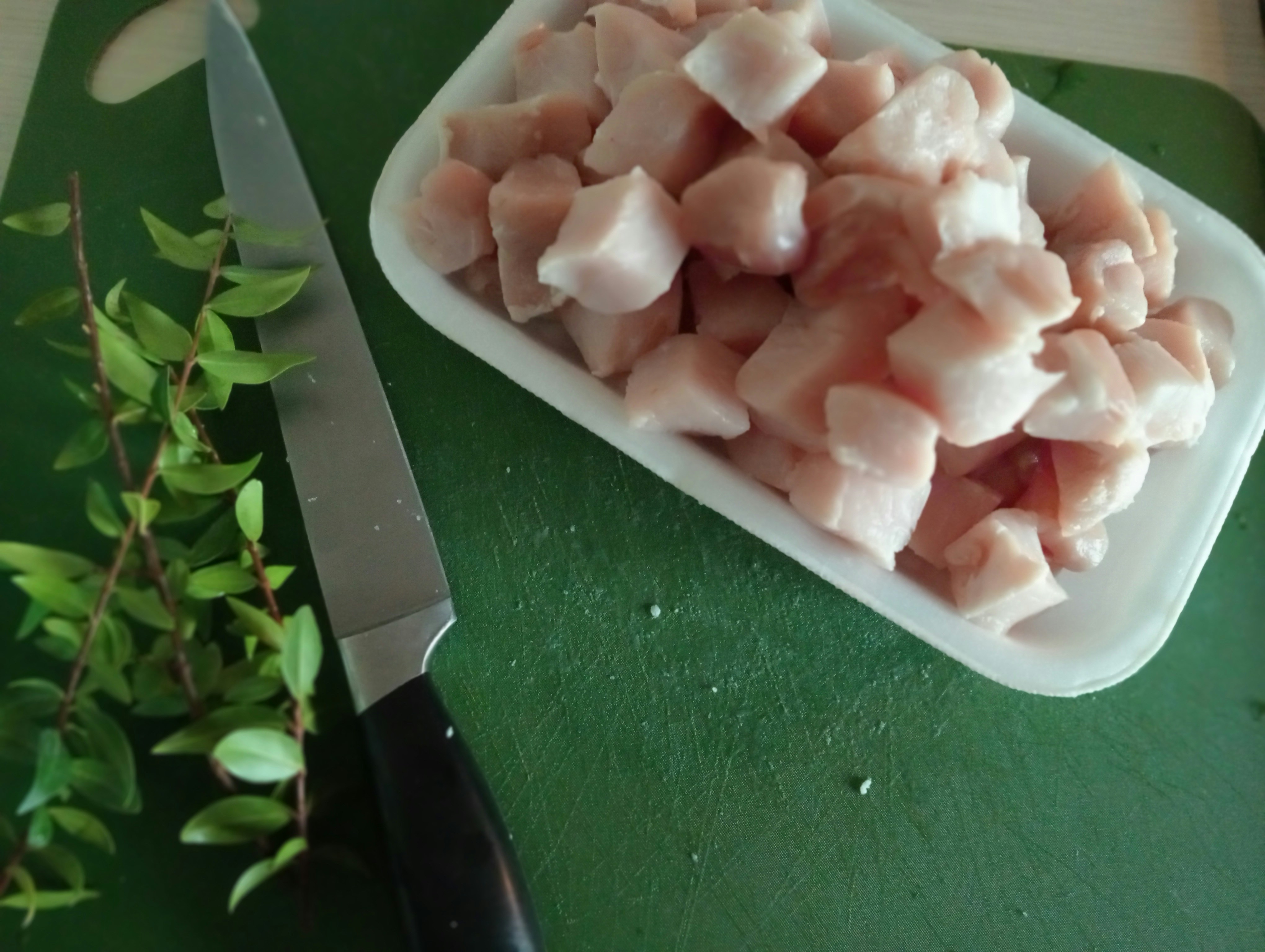 Fresh cut chicken pieces neatly arranged on clean white cutting board, bright airy kitchen, professional presentation