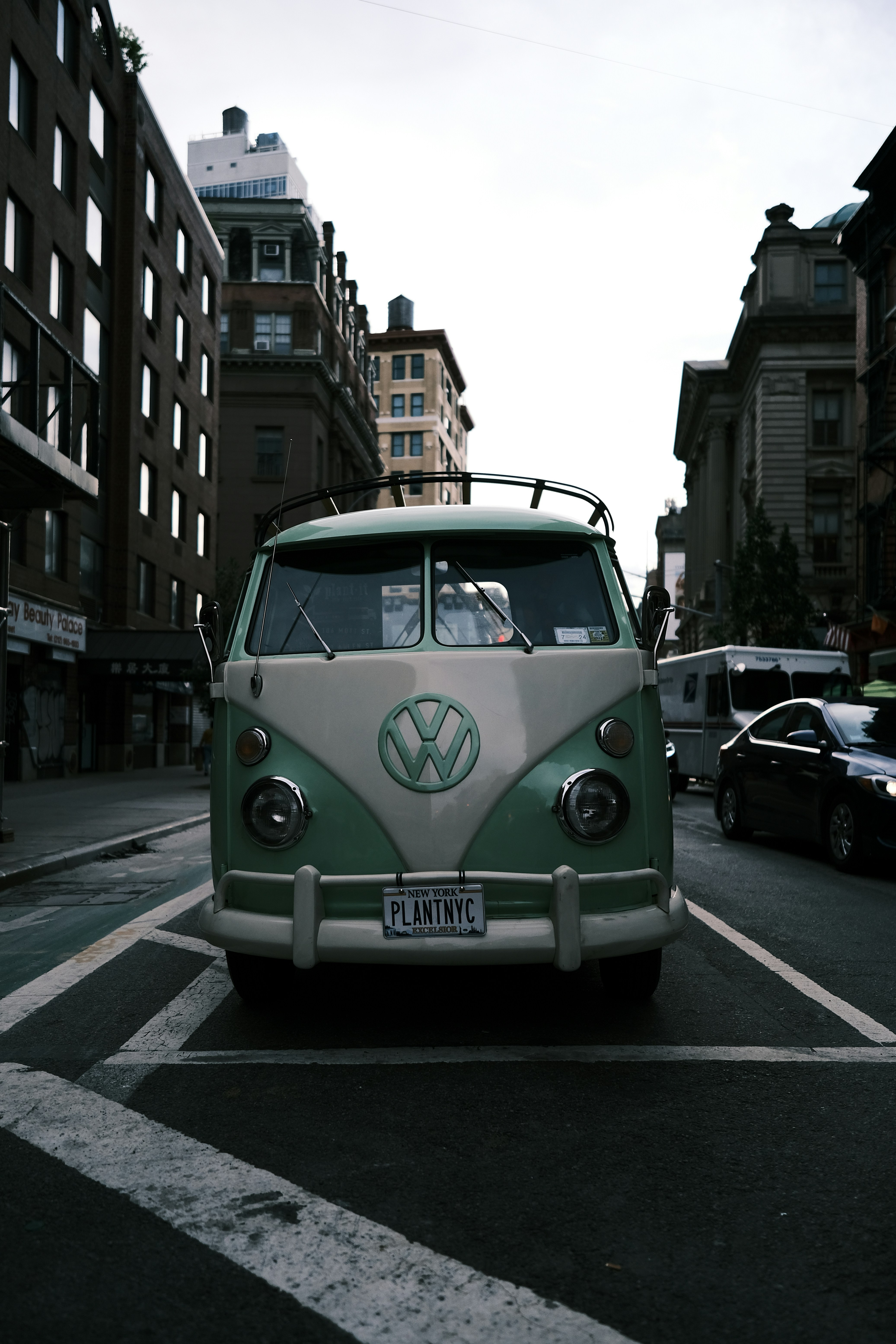 A vw bus driving down a street next to tall buildings