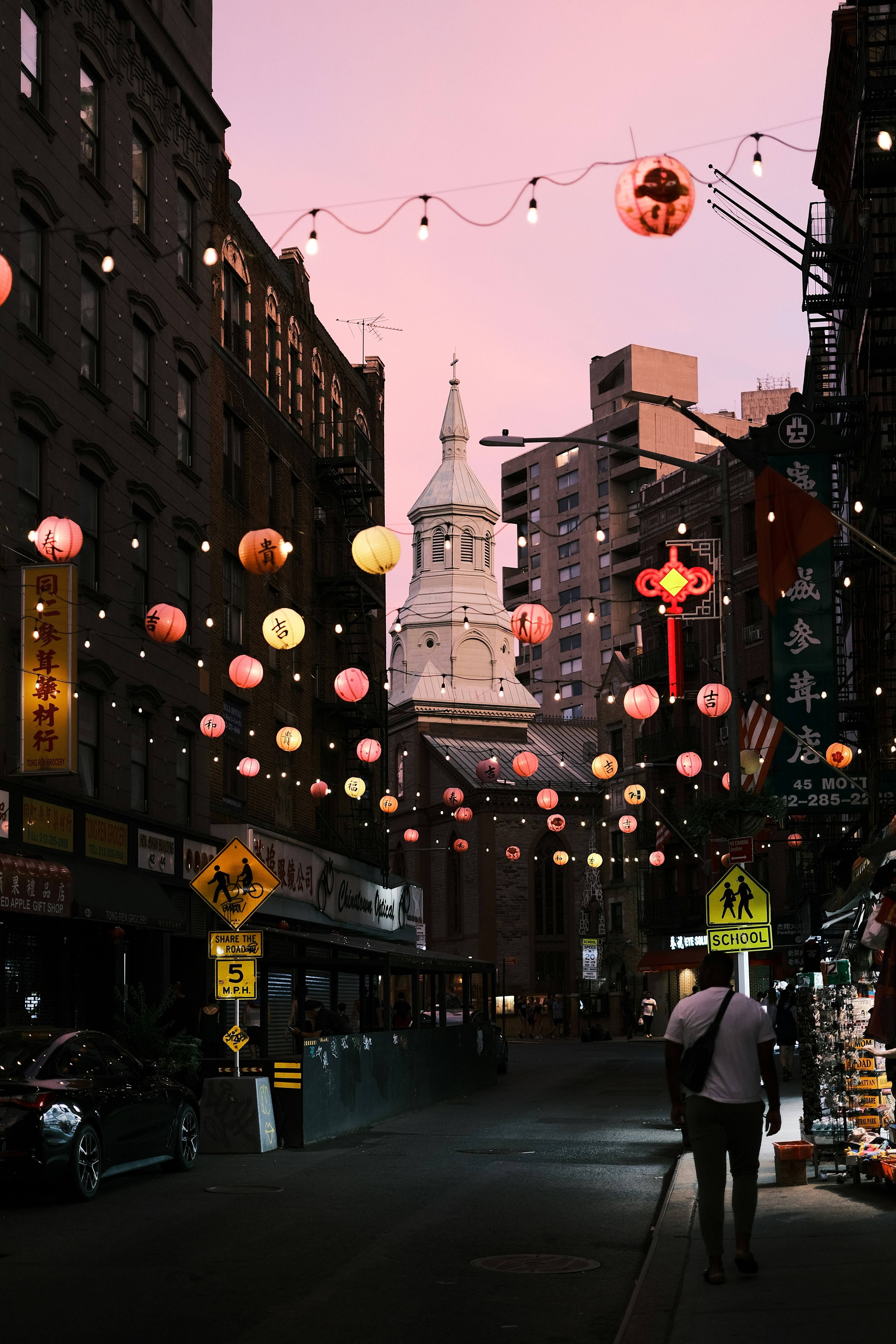 A man walking down a street next to tall buildings
