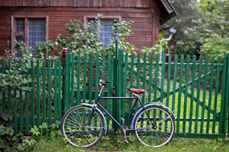 A bicycle parked in front of a green fence