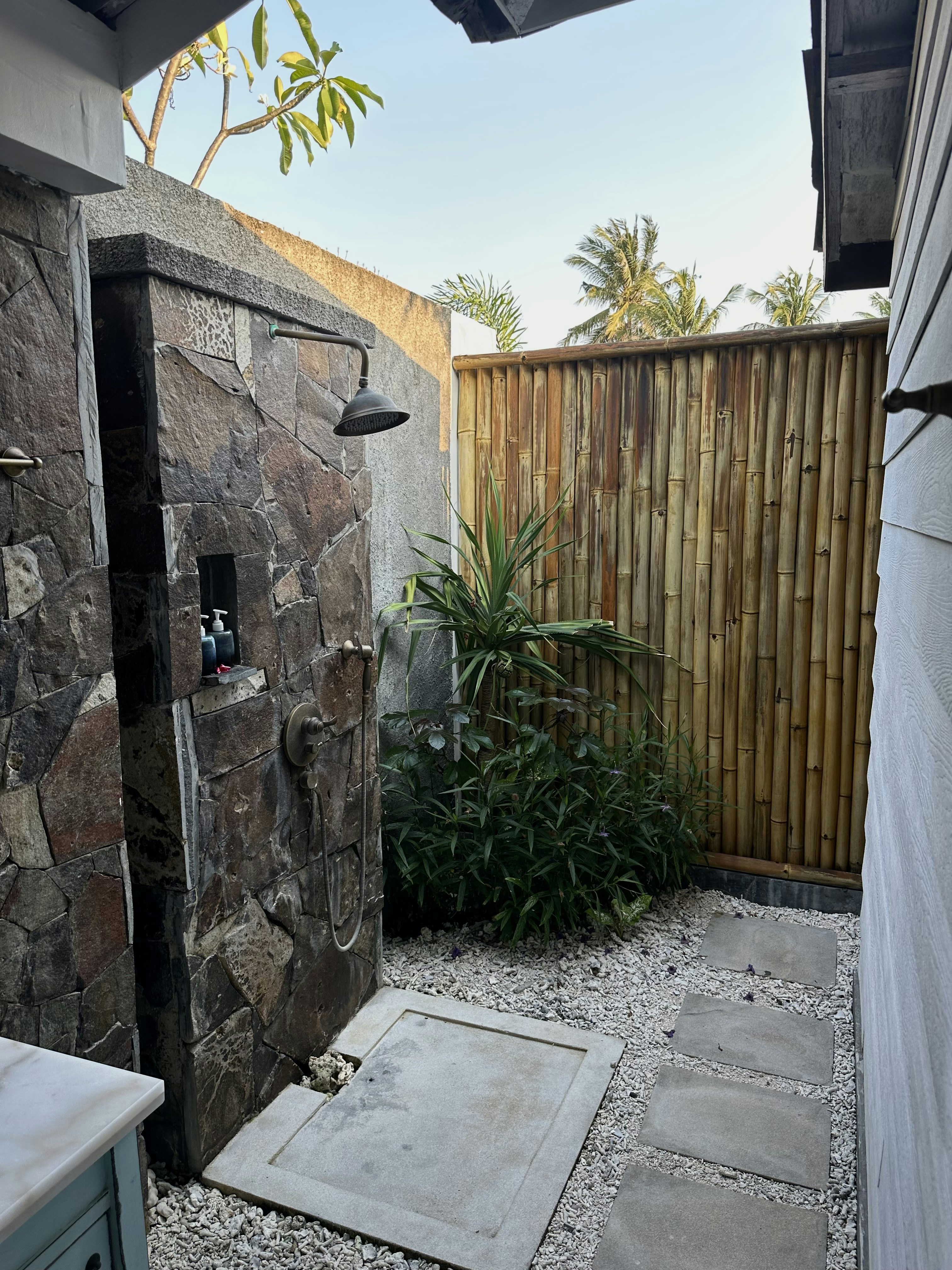 Modern tropical bathroom with rain shower and natural stone walls