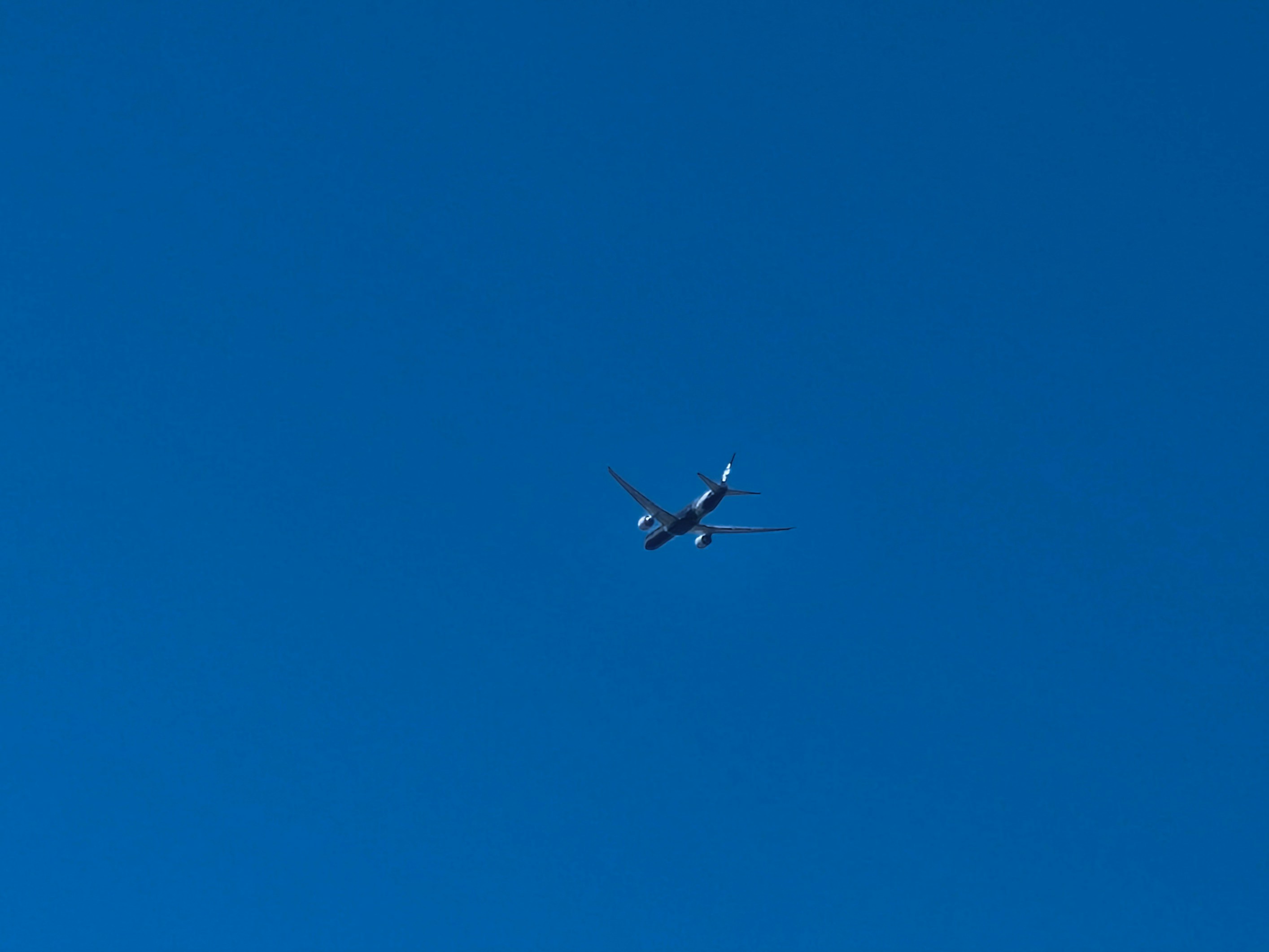 An airplane is flying in the blue sky