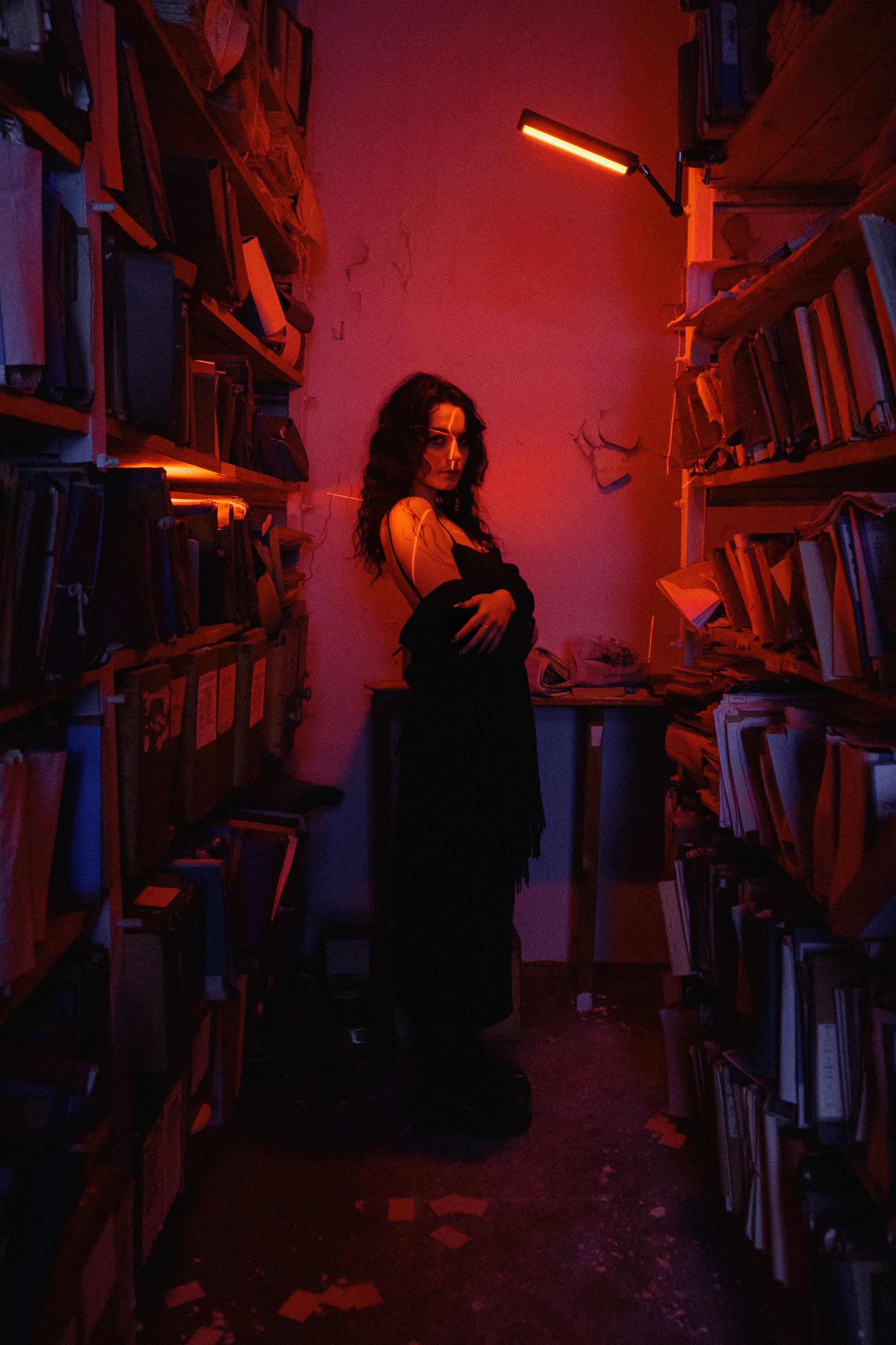 A woman standing in a dark room with a lot of books