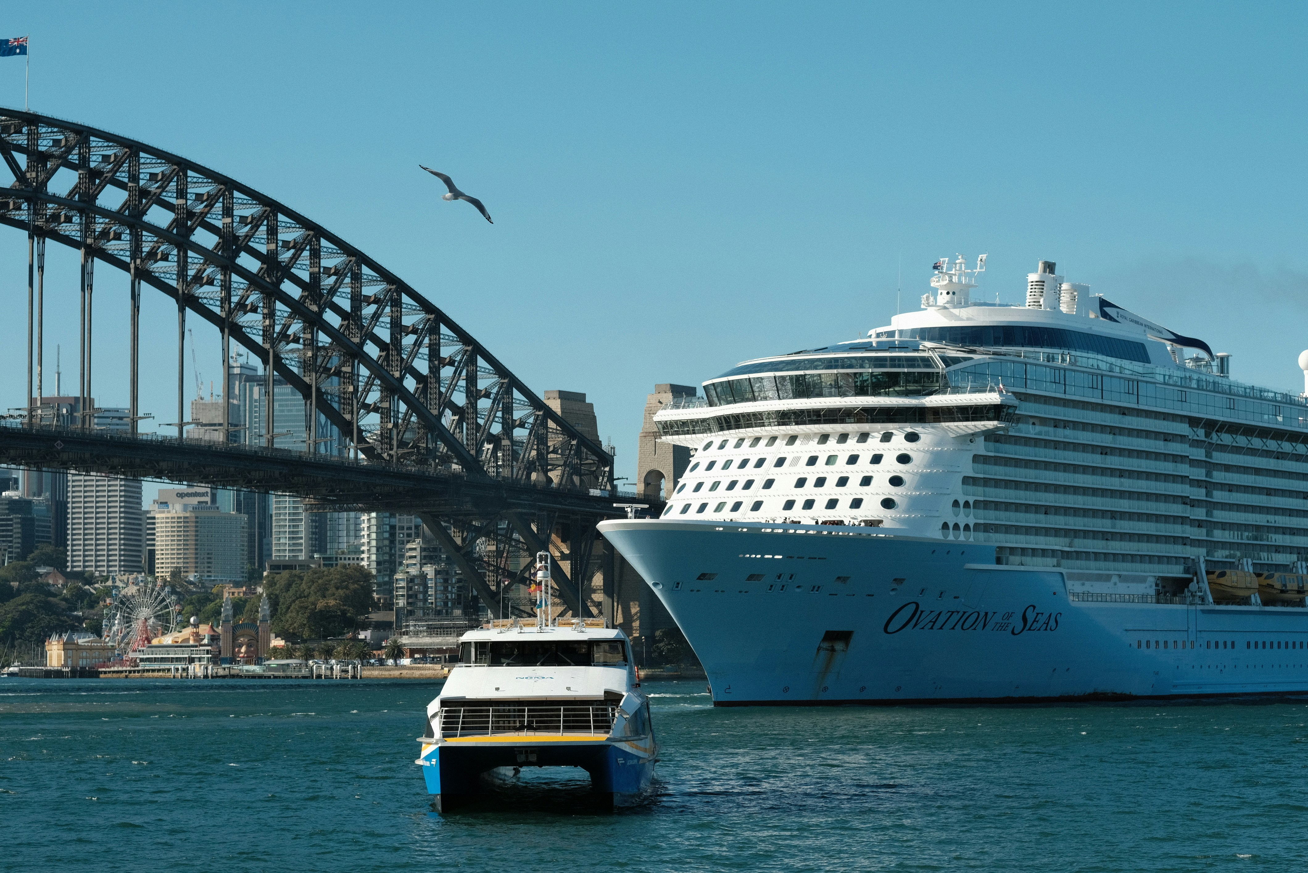 A cruise ship in the water with a bridge in the background