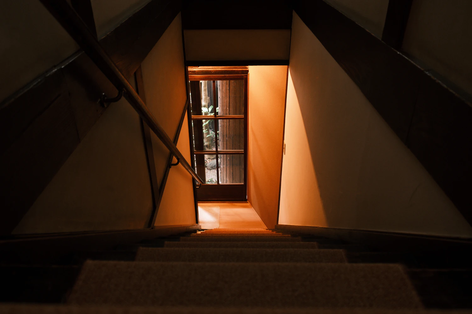Looking down the stairwell to the lit landing and the glazed door at the bottom