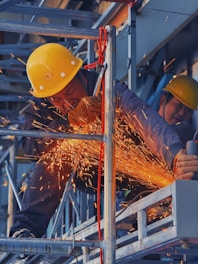 A man in a hard hat grinding metal with a grinder
