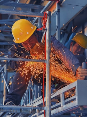 A man in a hard hat grinding metal with a grinder