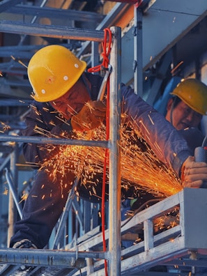 A man in a hard hat grinding metal with a grinder