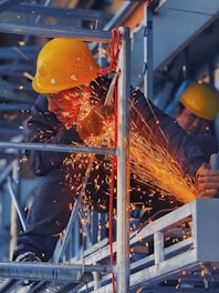 A man in a hard hat grinding metal with a grinder