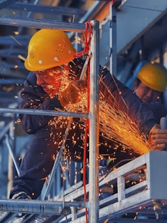 A man in a hard hat grinding metal with a grinder