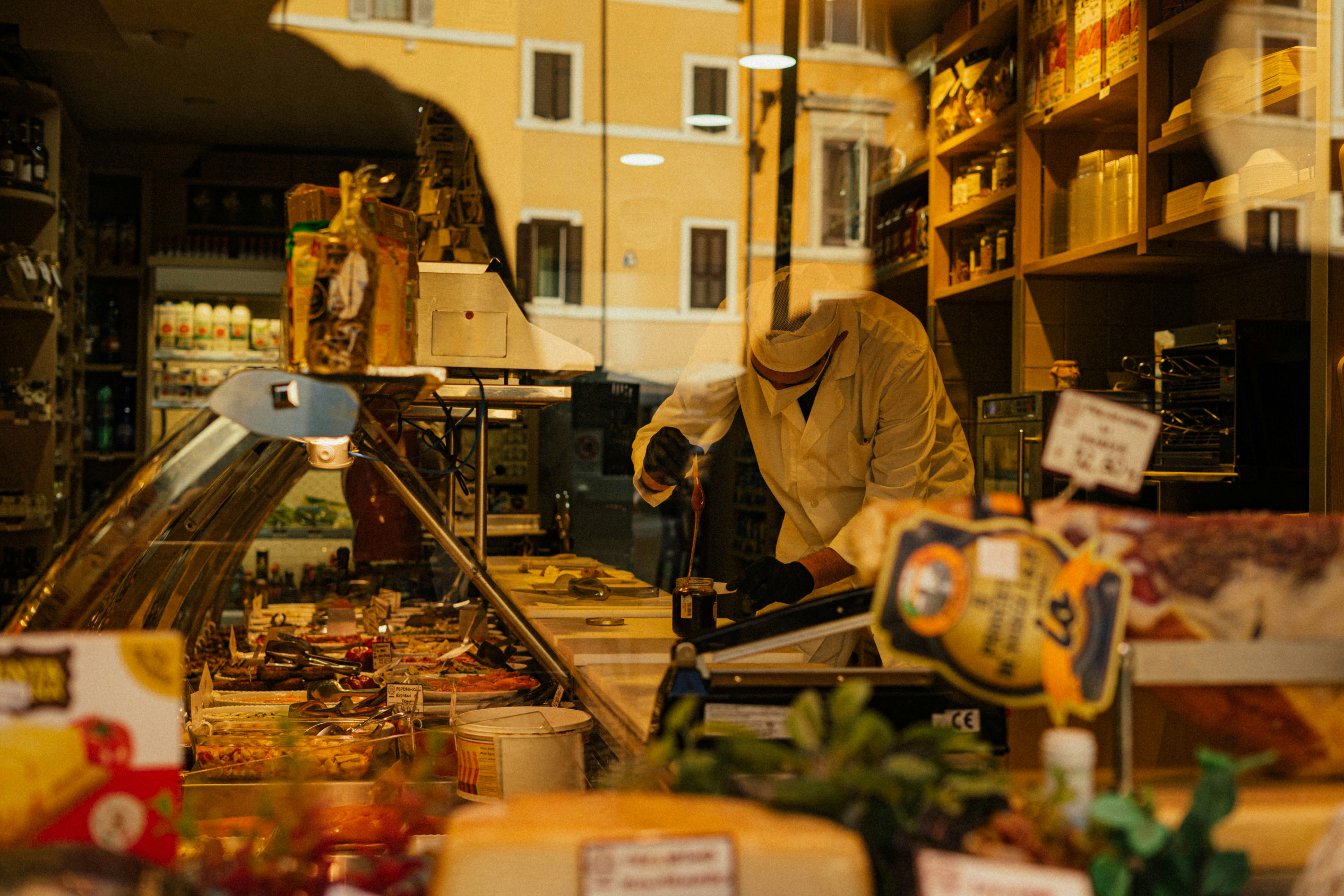 A man standing in front of a store filled with lots of food