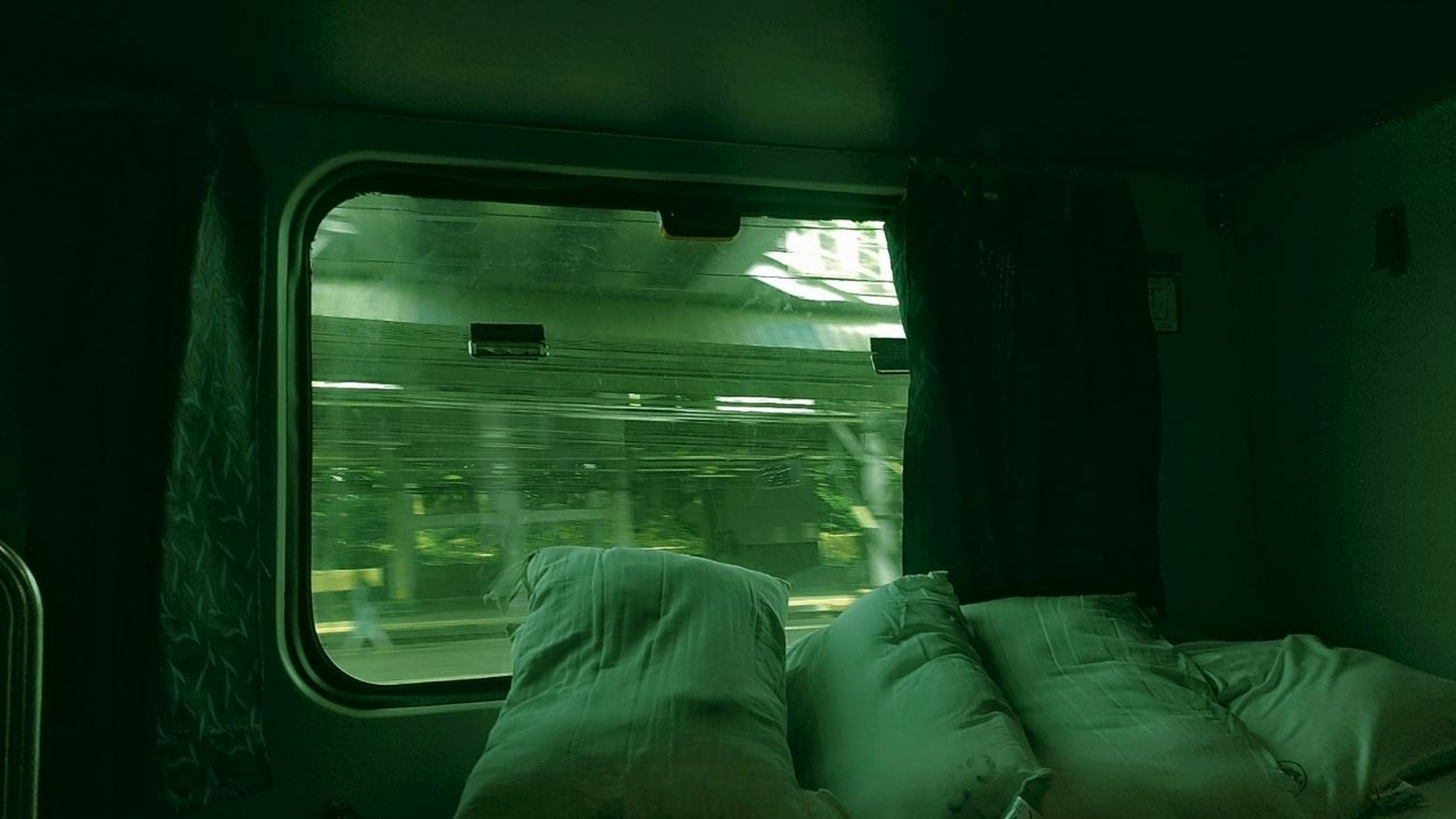 Luxurious private train cabin with plush velvet seating in deep burgundy, brass reading lamp, monogrammed pillows, and panoramic window showing passing landscape