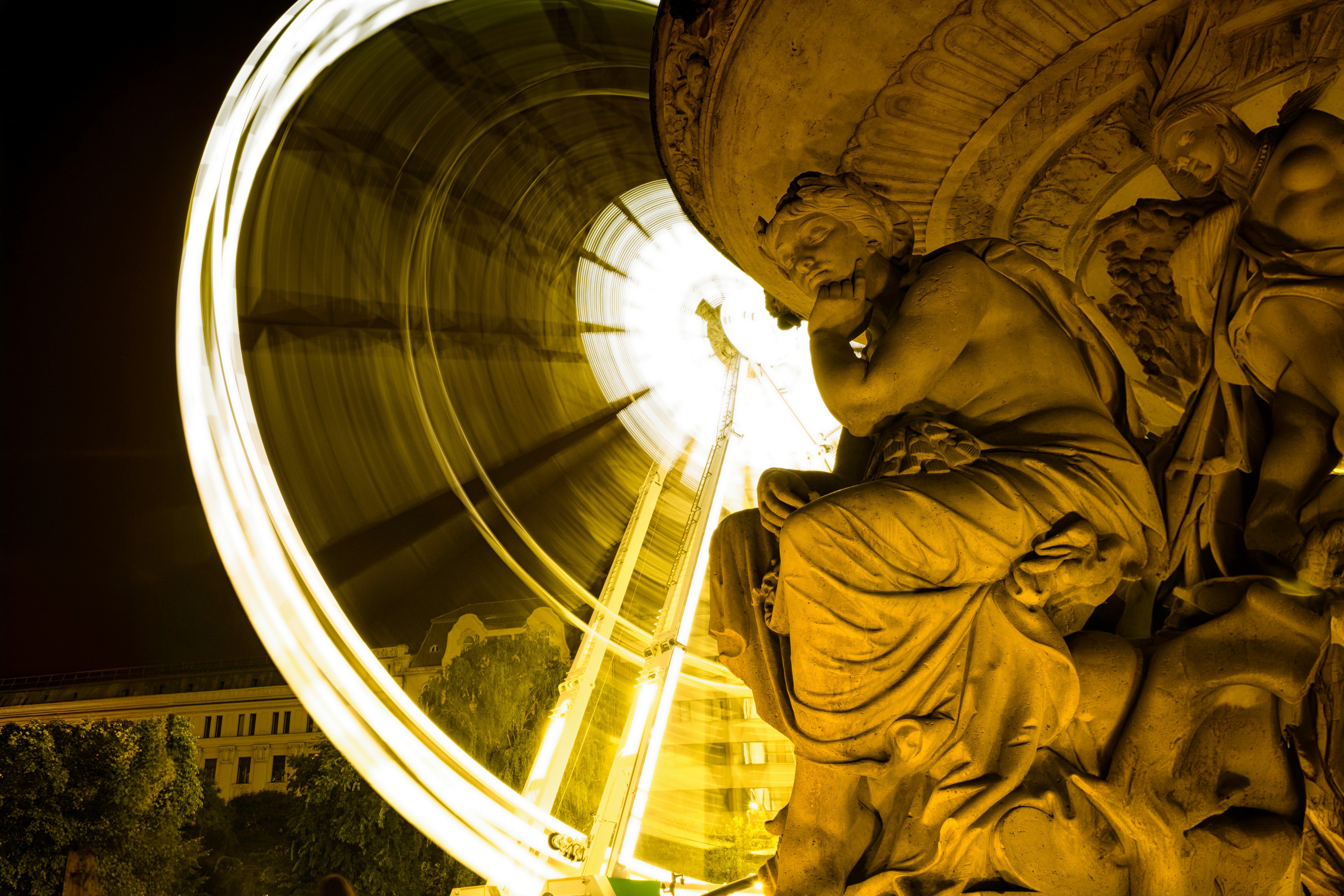 A statue of a man riding a ferris wheel at night