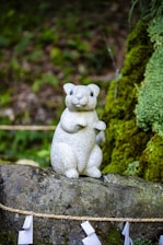 A small white bear sitting on top of a rock