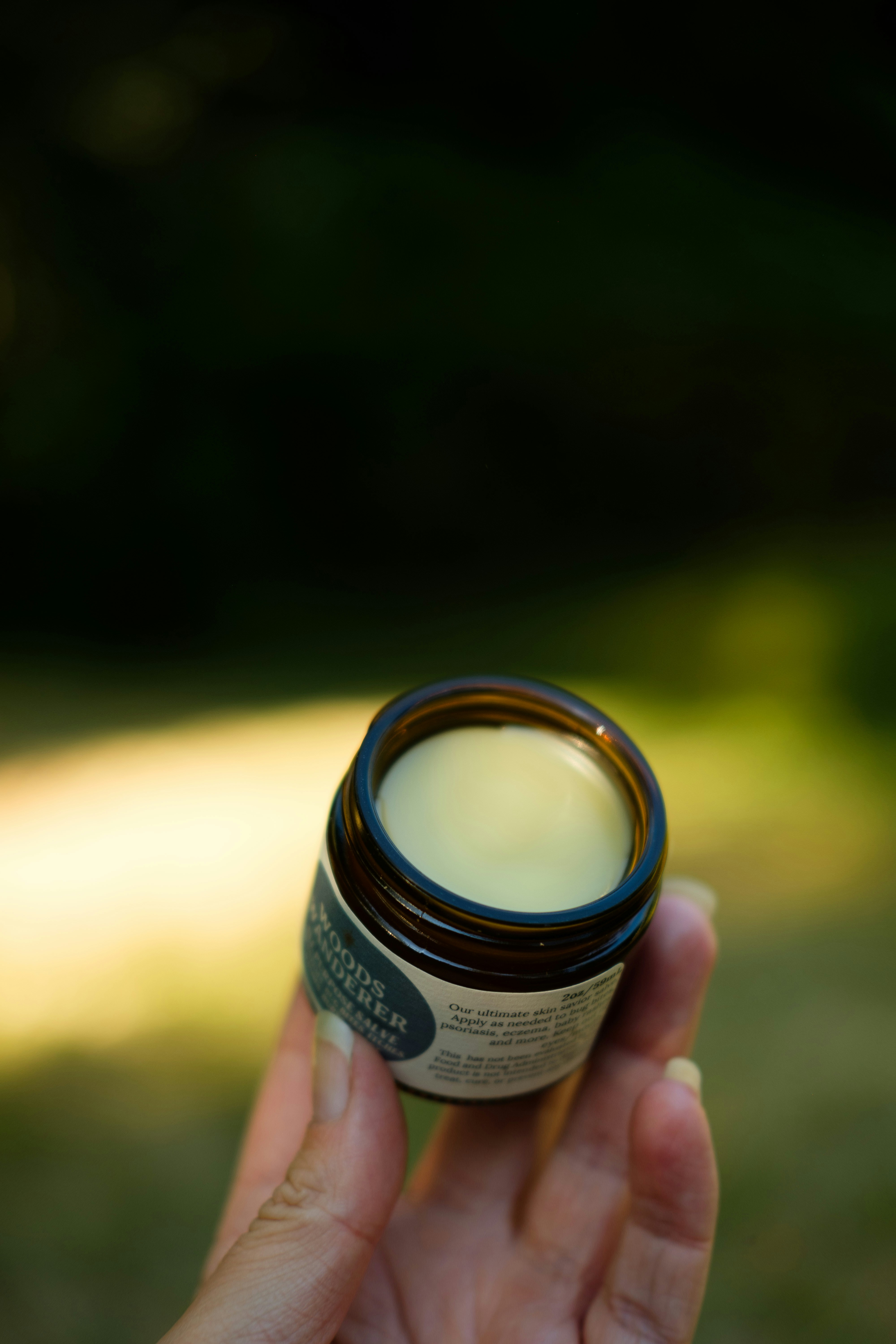 A person holding a jar of cream in their hand