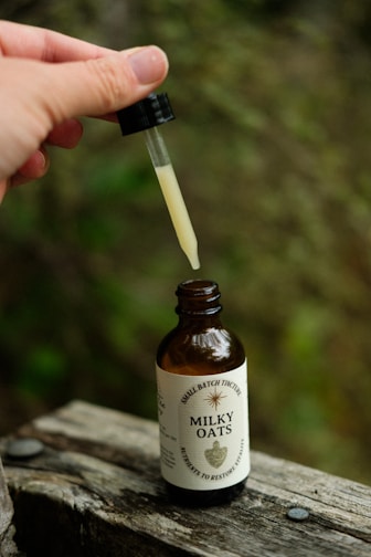 A person is holding a small bottle with a dropper