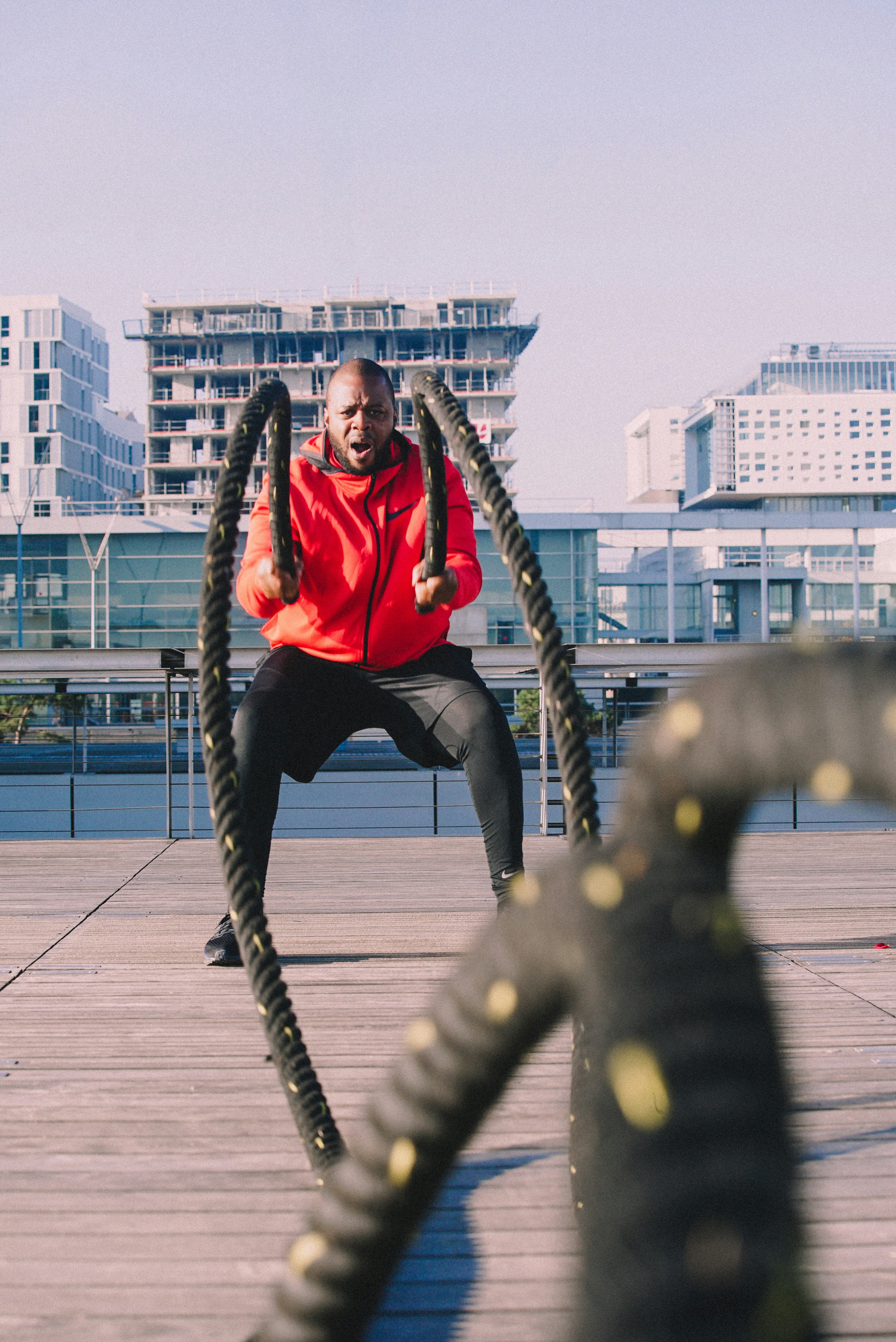 A man in a red shirt is doing exercises with a rope