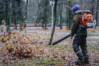 A man with a backpack and a chainsaw in the woods